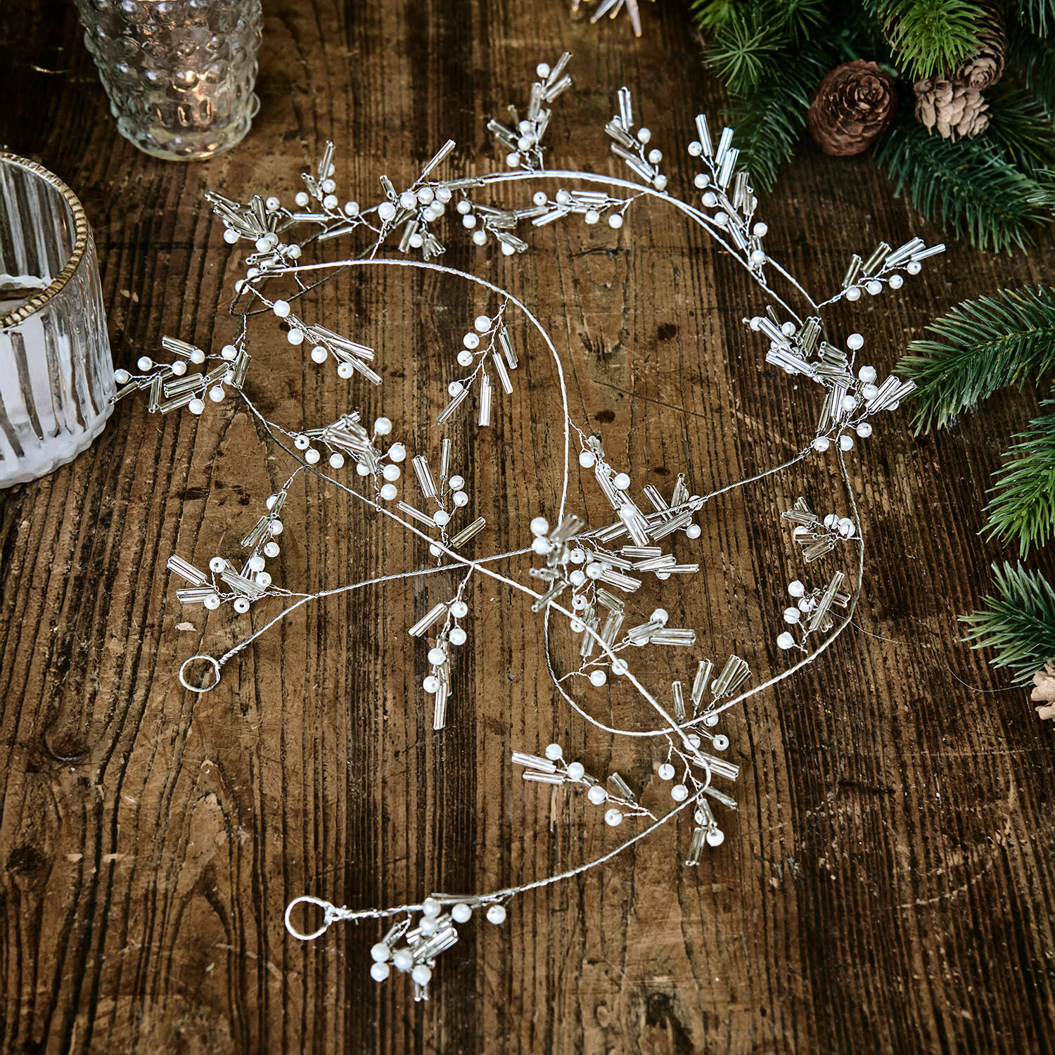 Guirlande Hybern Guirlande décorative argentée avec perles blanches posée sur une table en bois, décoration festive
