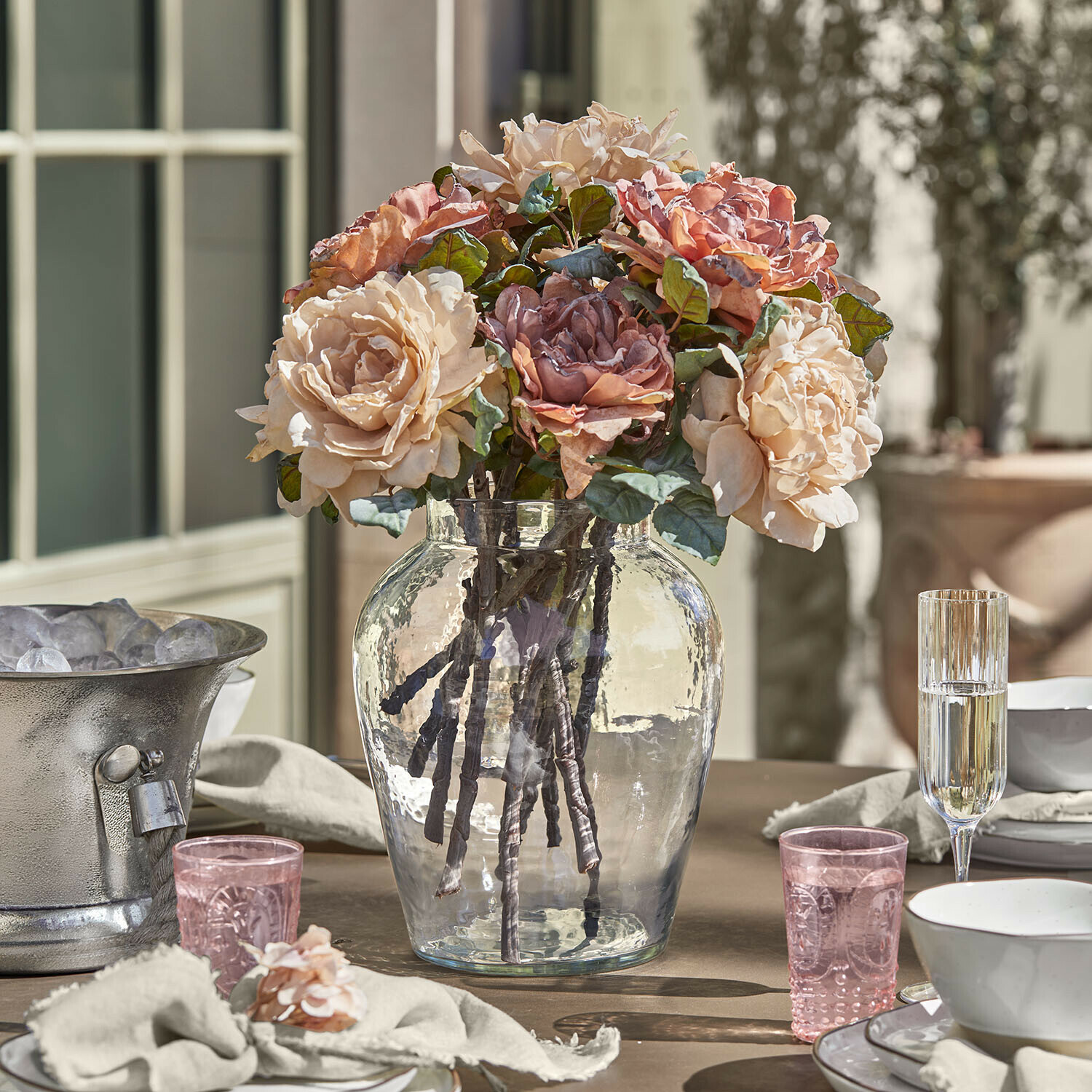 Vase Lunaras Bouquet de roses beige et rose dans un vase en verre transparent sur une table dressée