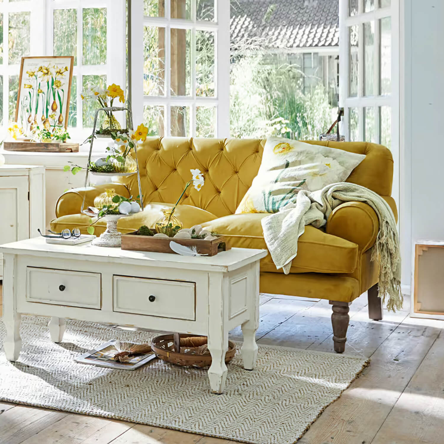 Geel fluwelen bank met doorgestikte rugleuning in lichte woonkamer met witte salontafel en decoraties