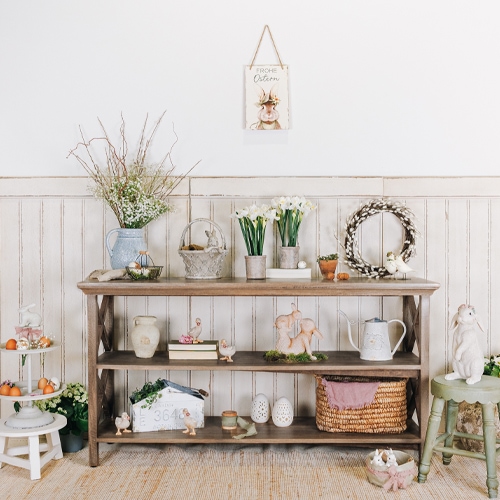 Étagère en bois avec décorations de Pâques, fleurs et panier en osier dans un intérieur clair
