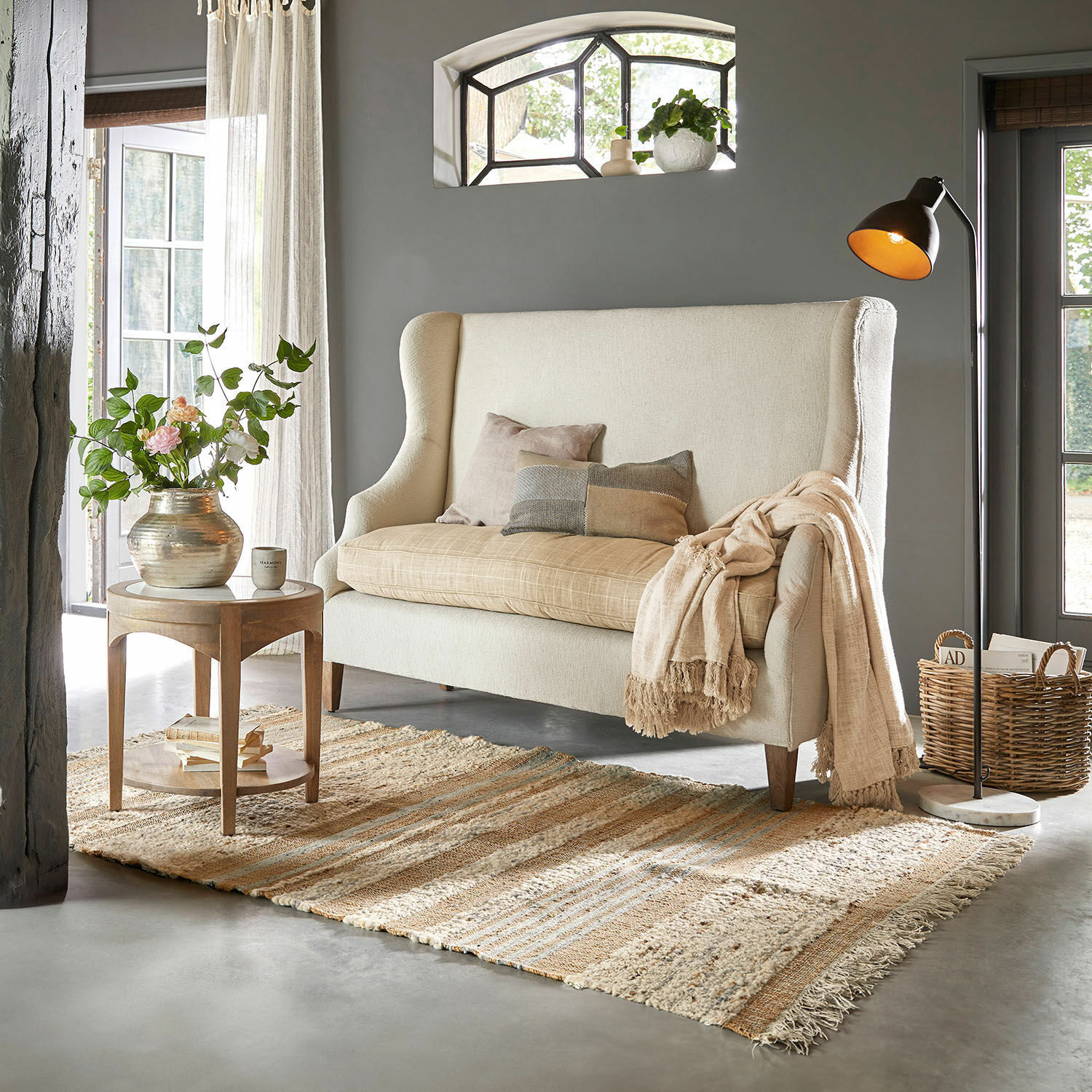 Tapis Cassidy Canapé beige à dossier haut avec coussins dans un salon chaleureux avec tapis et lampe sur pied