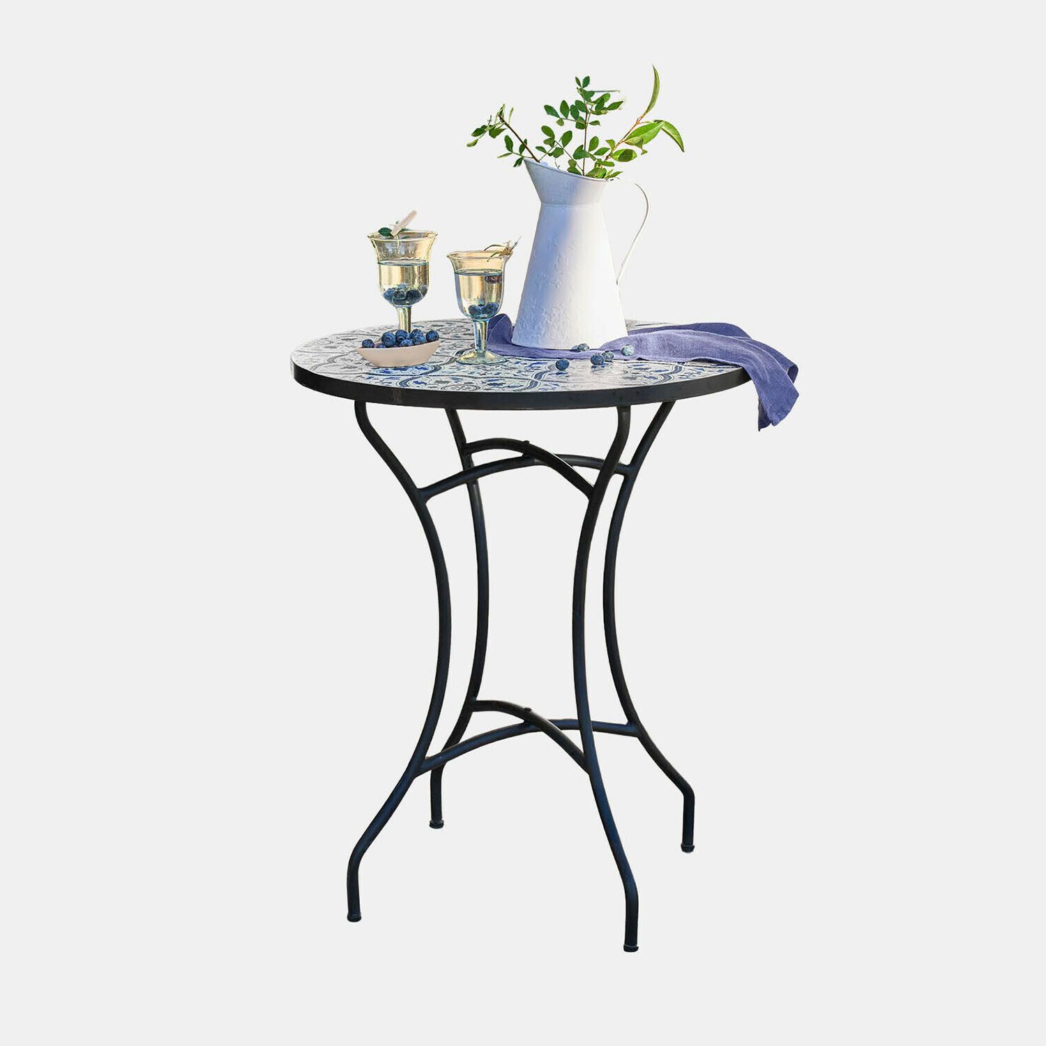 Tafel Giulessa Ronde tafel met metalen poten en wit-blauw mozaïekblad, gedecoreerd met kan en glazen