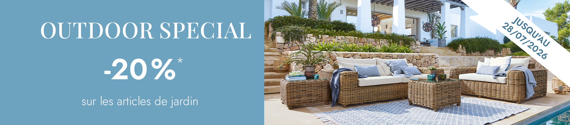 Ensemble de meubles de jardin en rotin naturel avec coussins clairs et tapis bleu sur terrasse extérieure