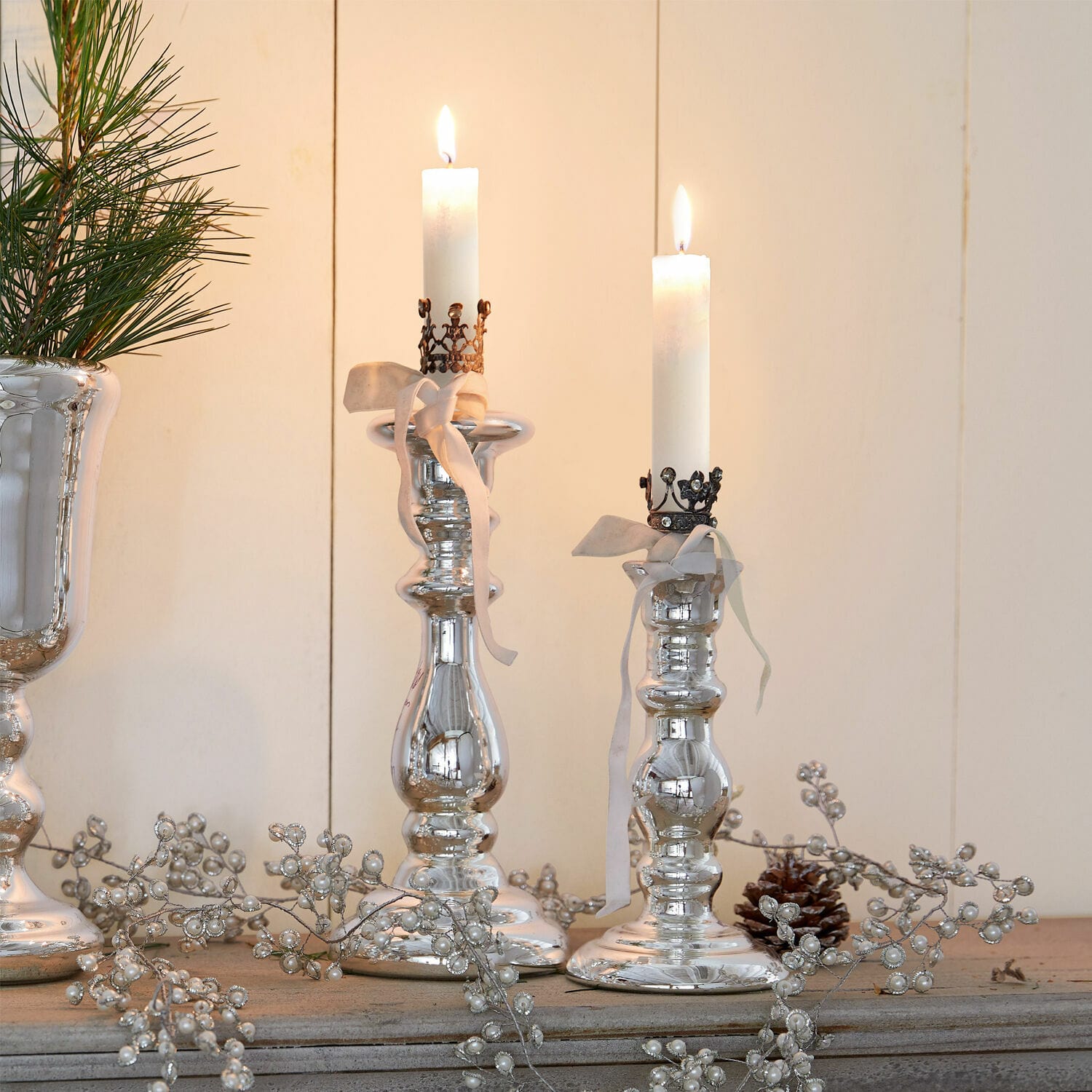Kandelaar set van 2 Gao Zilveren kandelaars met witte kaarsen en decoratieve linten op rustiek houten oppervlak