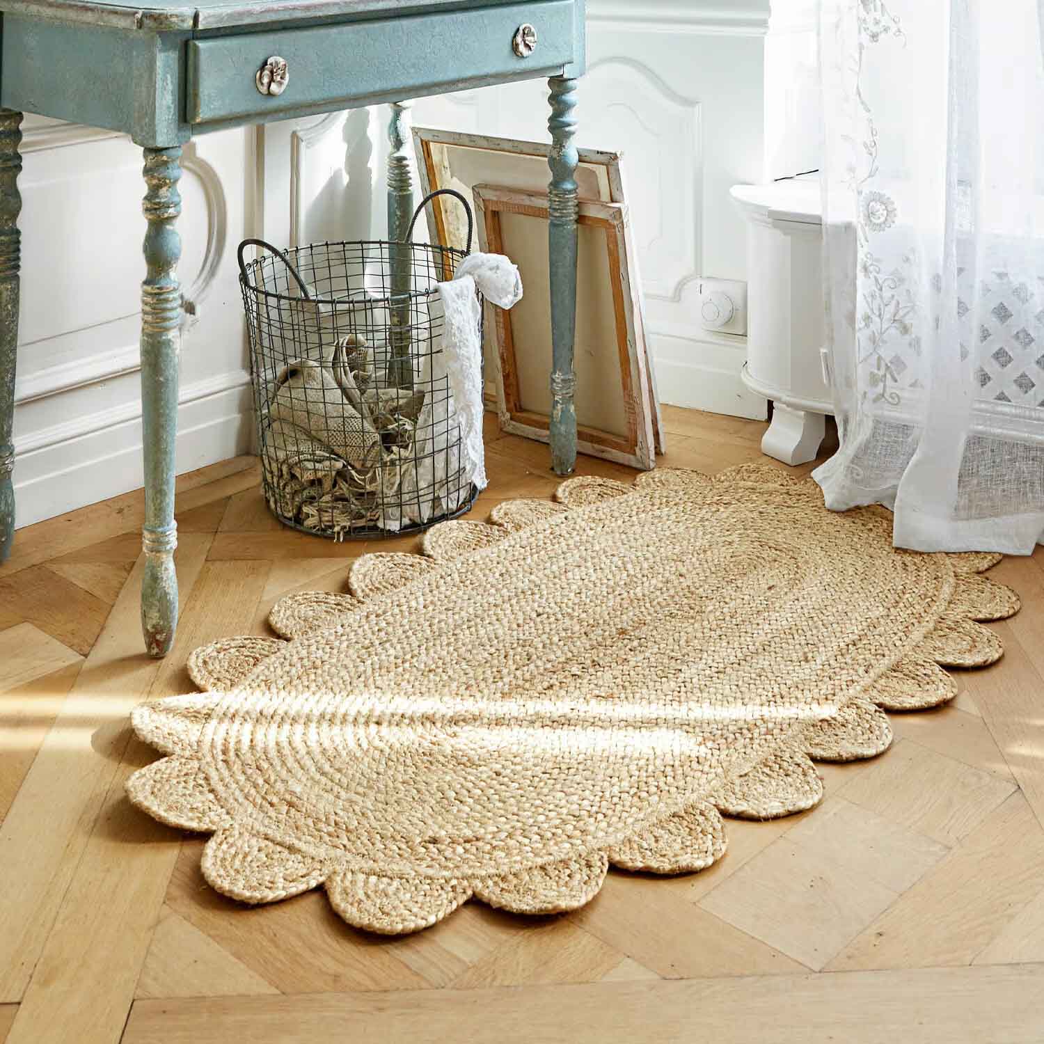 Ovale jute vloerkleed in natuurlijke kleur met decoratieve gegolfde rand op lichte houten vloer
