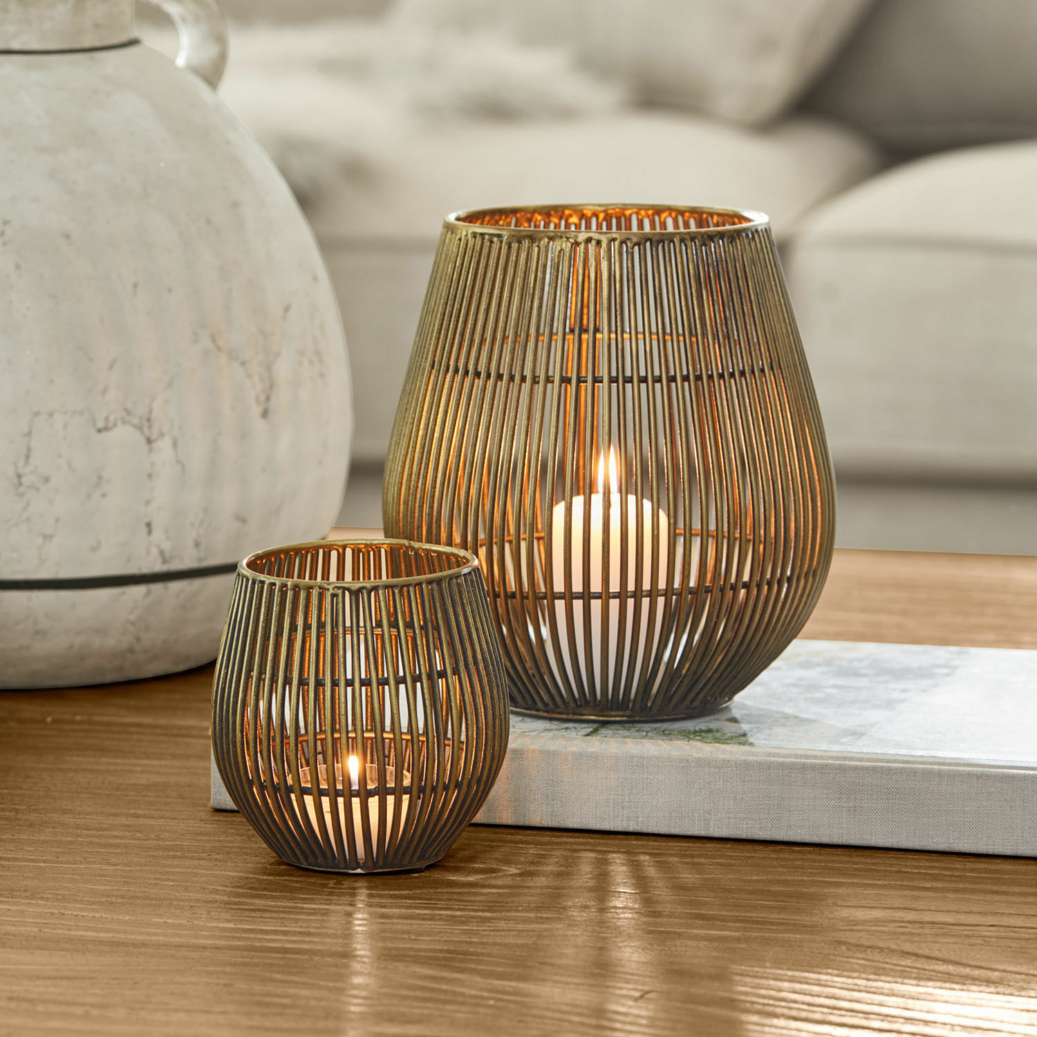 Lot de 2 photophores Pontarino Deux lanternes en métal couleur laiton avec des barreaux verticaux, bougies allumées à l'intérieur, décoration de table