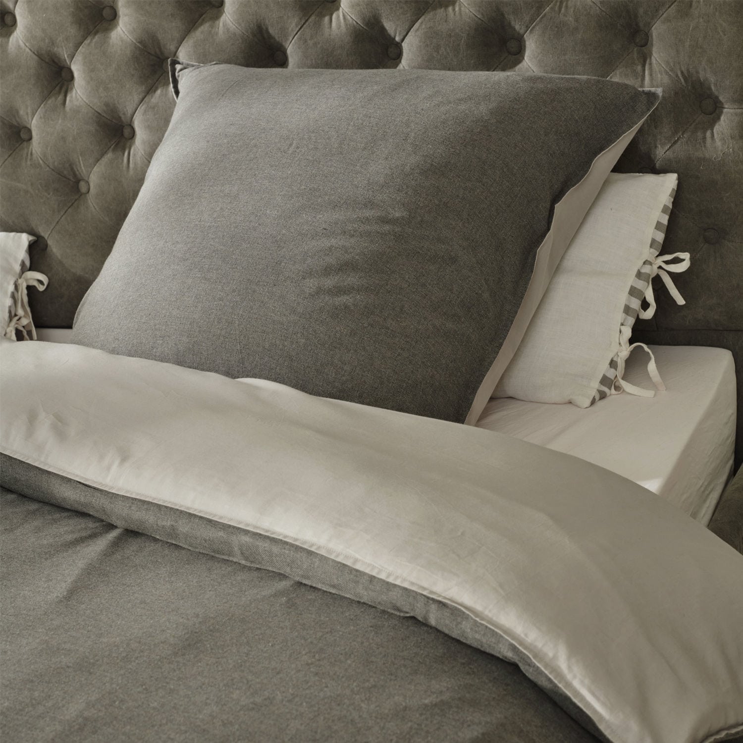 Parure de lit Mynatt Parure de lit grise en tissu doux sur un lit avec tête de lit capitonnée, confortable et élégante