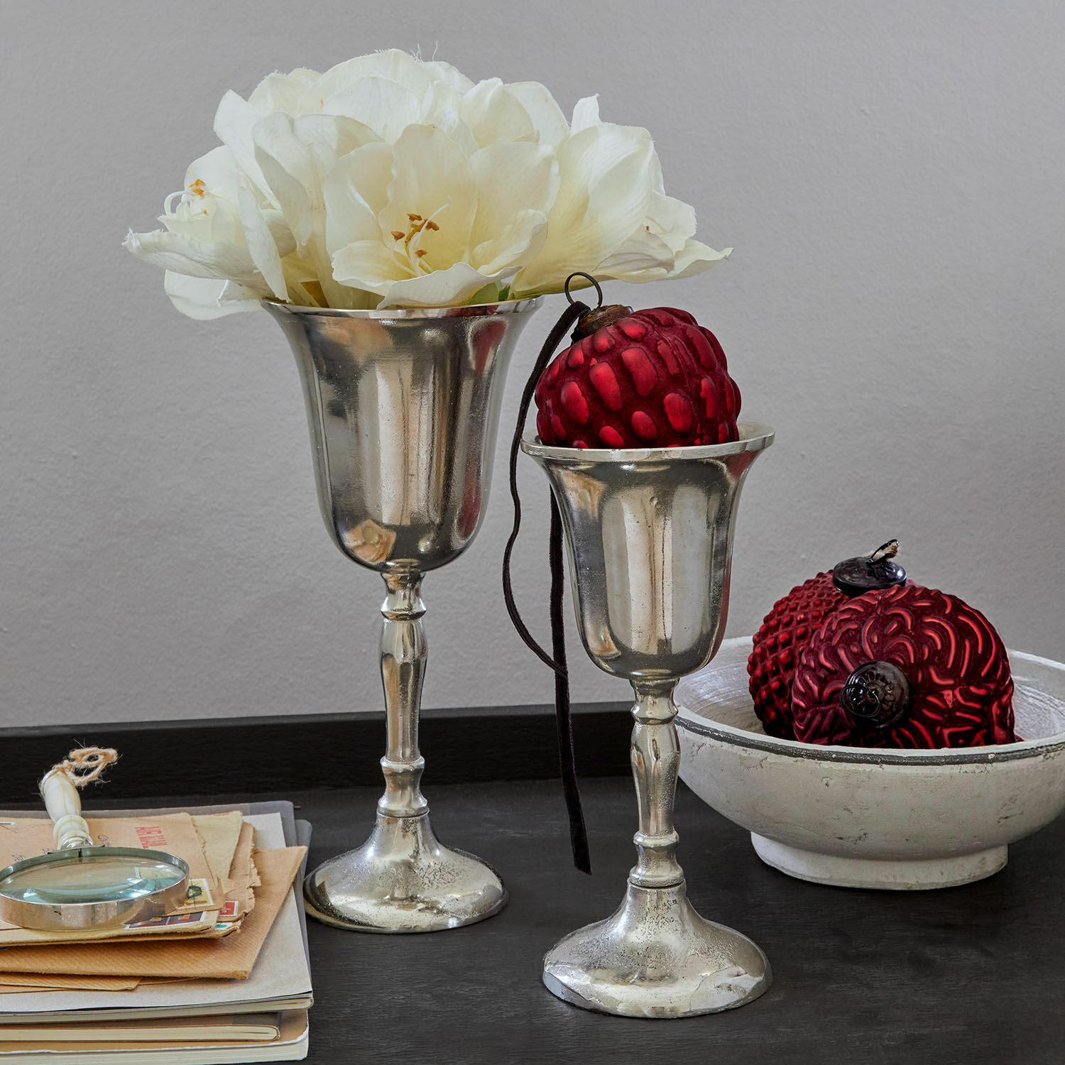 Lot de 2 vases Solérie Deux coupes argentées décoratives avec fleurs blanches et ornements rouges sur table noire