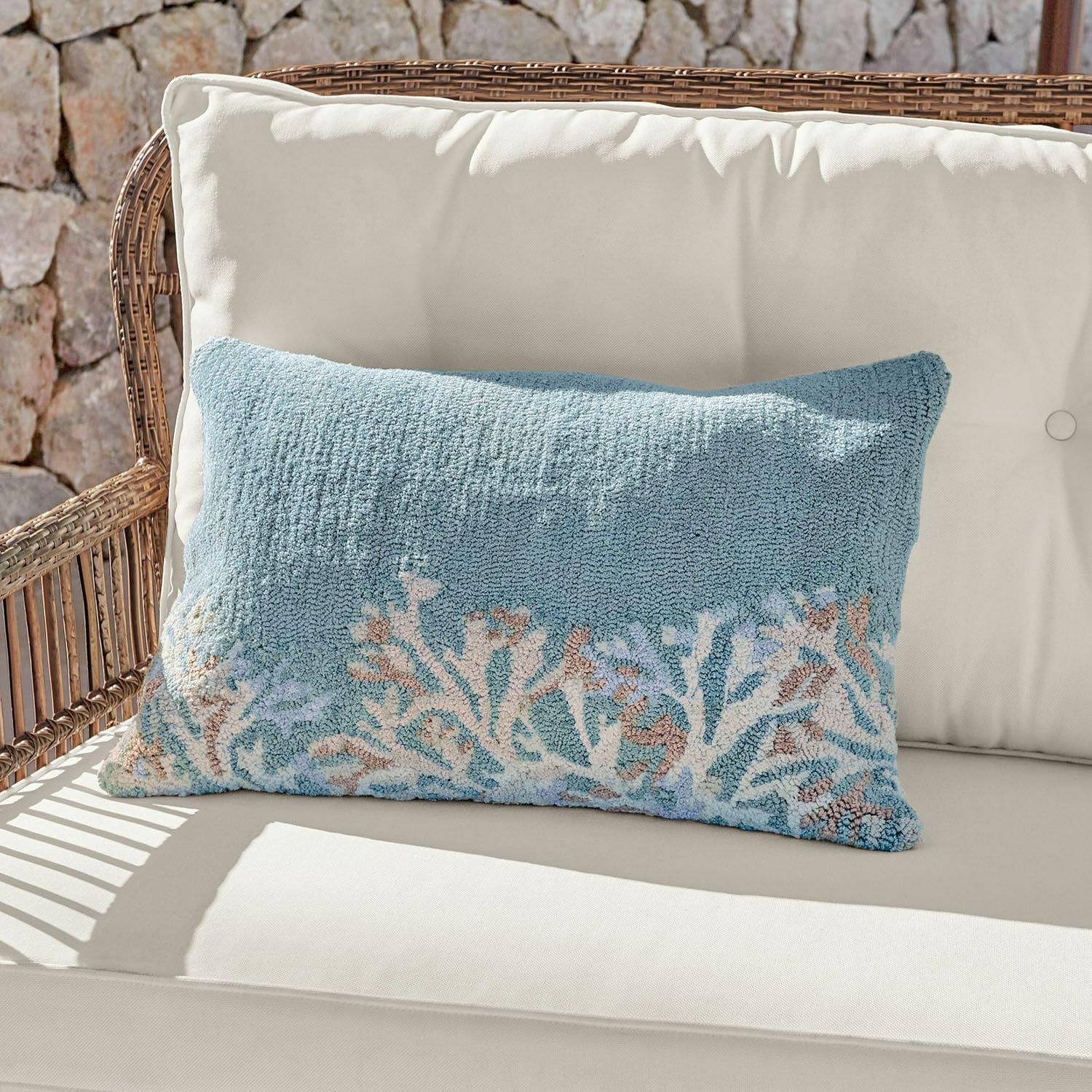 Kussenhoes voor binnen & buiten Dorlancourt Decoratief kussen van zacht materiaal in blauw met koraalmotief op lichte rotanbank.