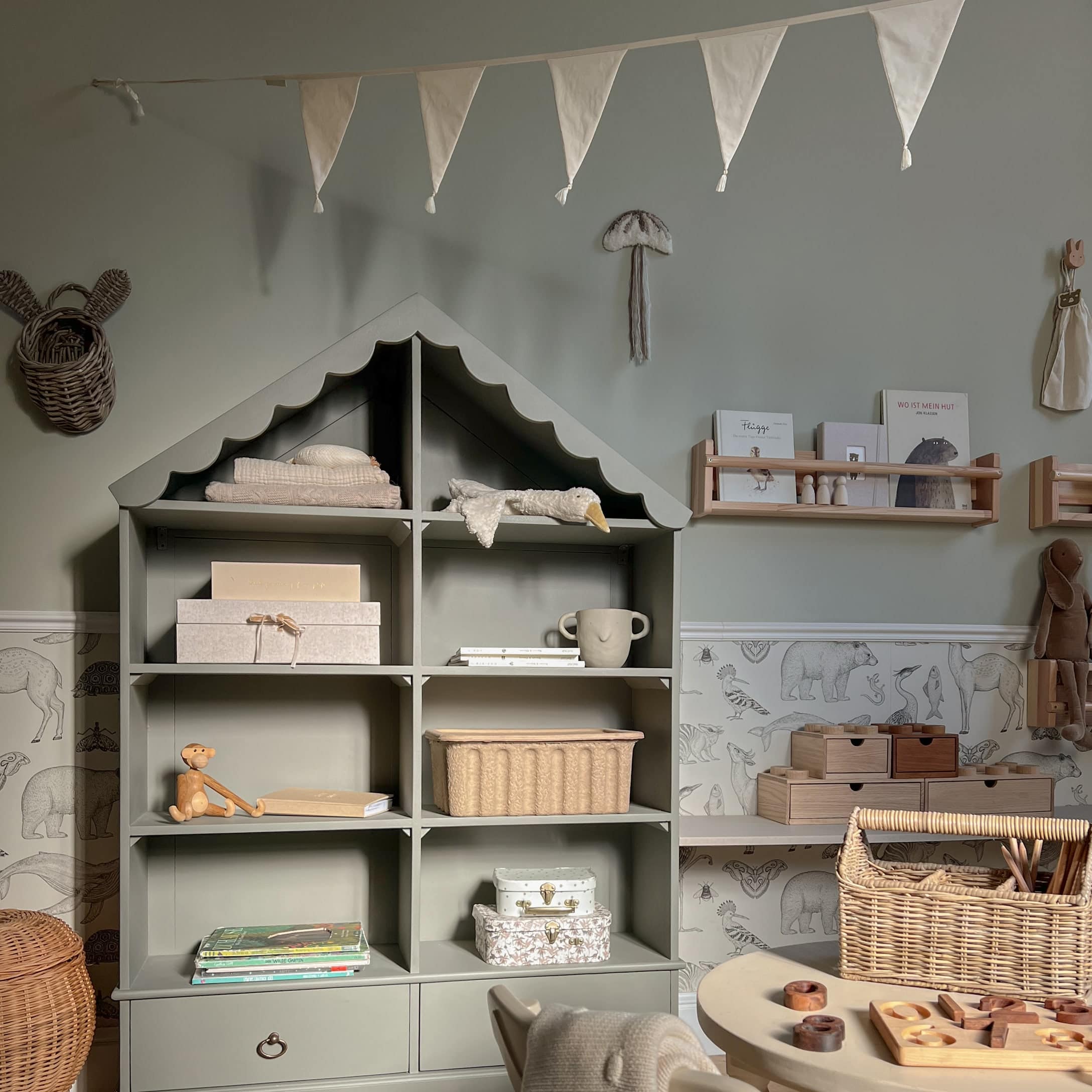 Grijze houten kast in huisvorm met decoraties en speelgoed in kinderkamer