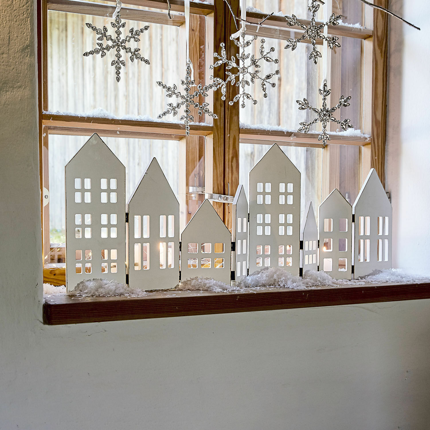 Decoratieve shutter Cottages Witte houten huisdecoratie op vensterbank met hangende sneeuwvlokken voor winterse sfeer