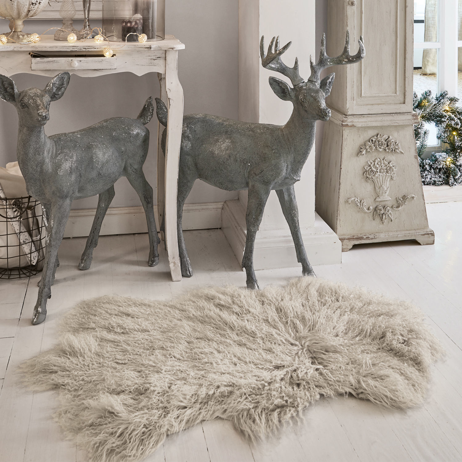 Peau d'agneau Gad Figurines décoratives de cerfs grises en métal près d'une table blanche et d'un tapis beige à poils longs