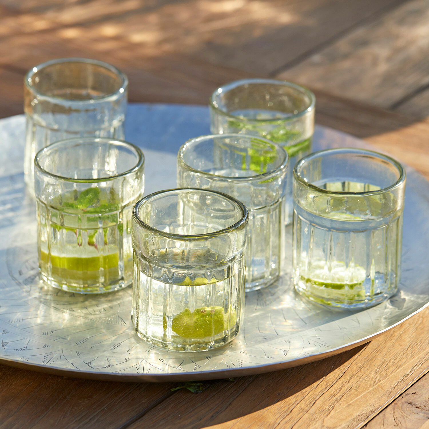 Glas set van 6 Roseville Zes doorzichtige glazen met limoen op een metalen dienblad op een houten tafel