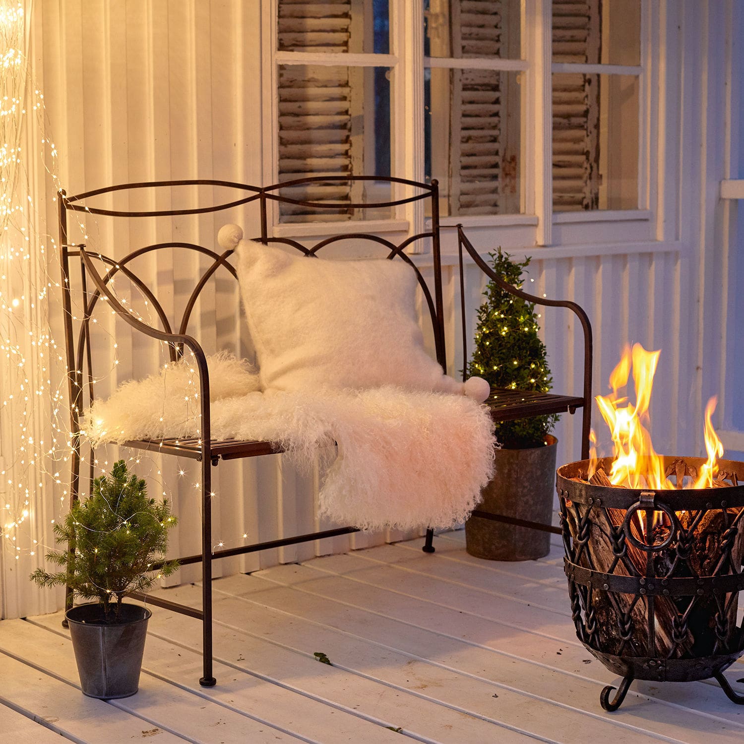 Banc Jablines Banc en métal avec coussin blanc et couverture en fourrure près d'un brasero sur une terrasse décorée de guirlandes lumineuses