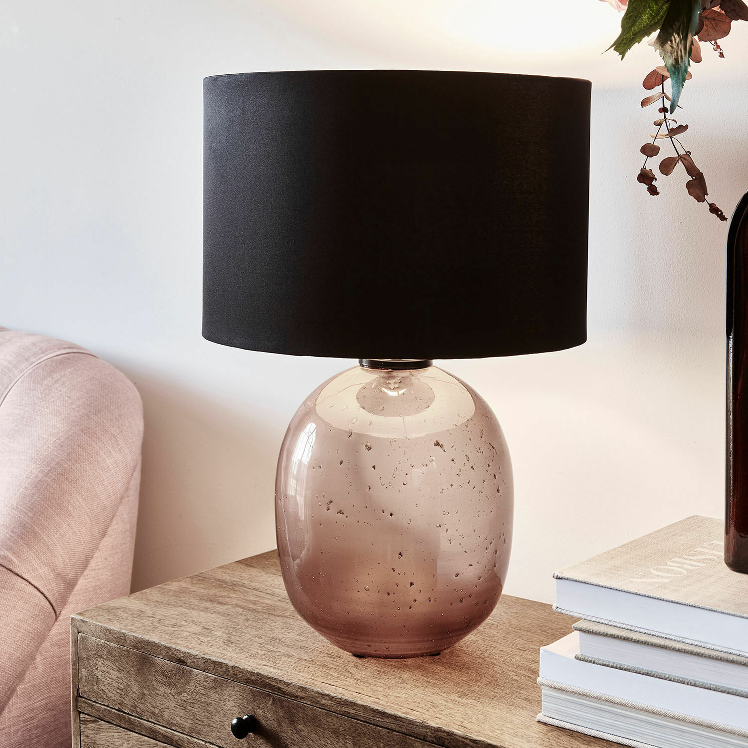 Lampe de table en verre transparent brun avec abat-jour noir posée sur une table en bois