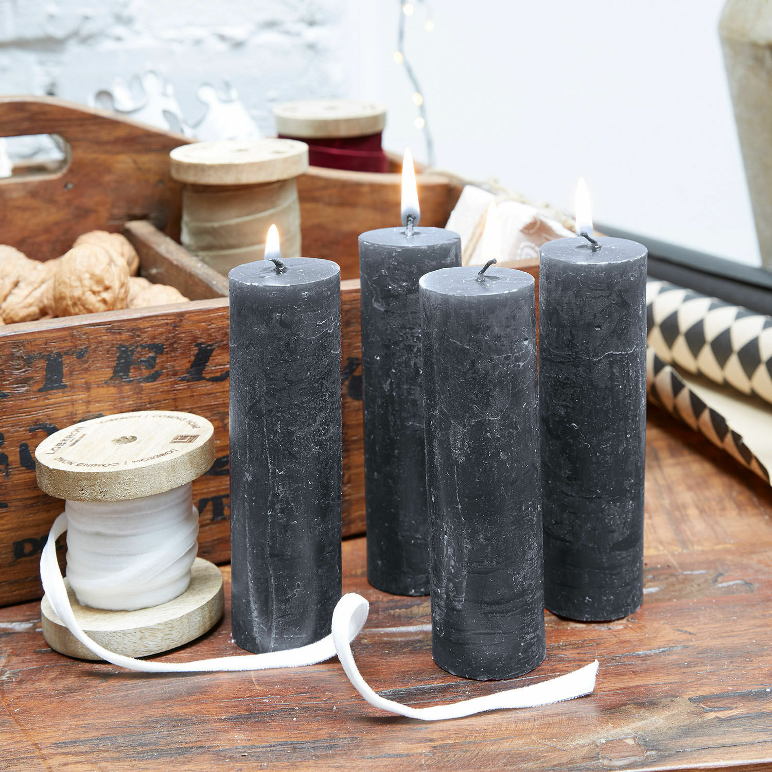 Kaars set van 4 Muriel Vier zwarte kaarsen van natuurlijke was op houten tafel met decoratieve spoelen en noten