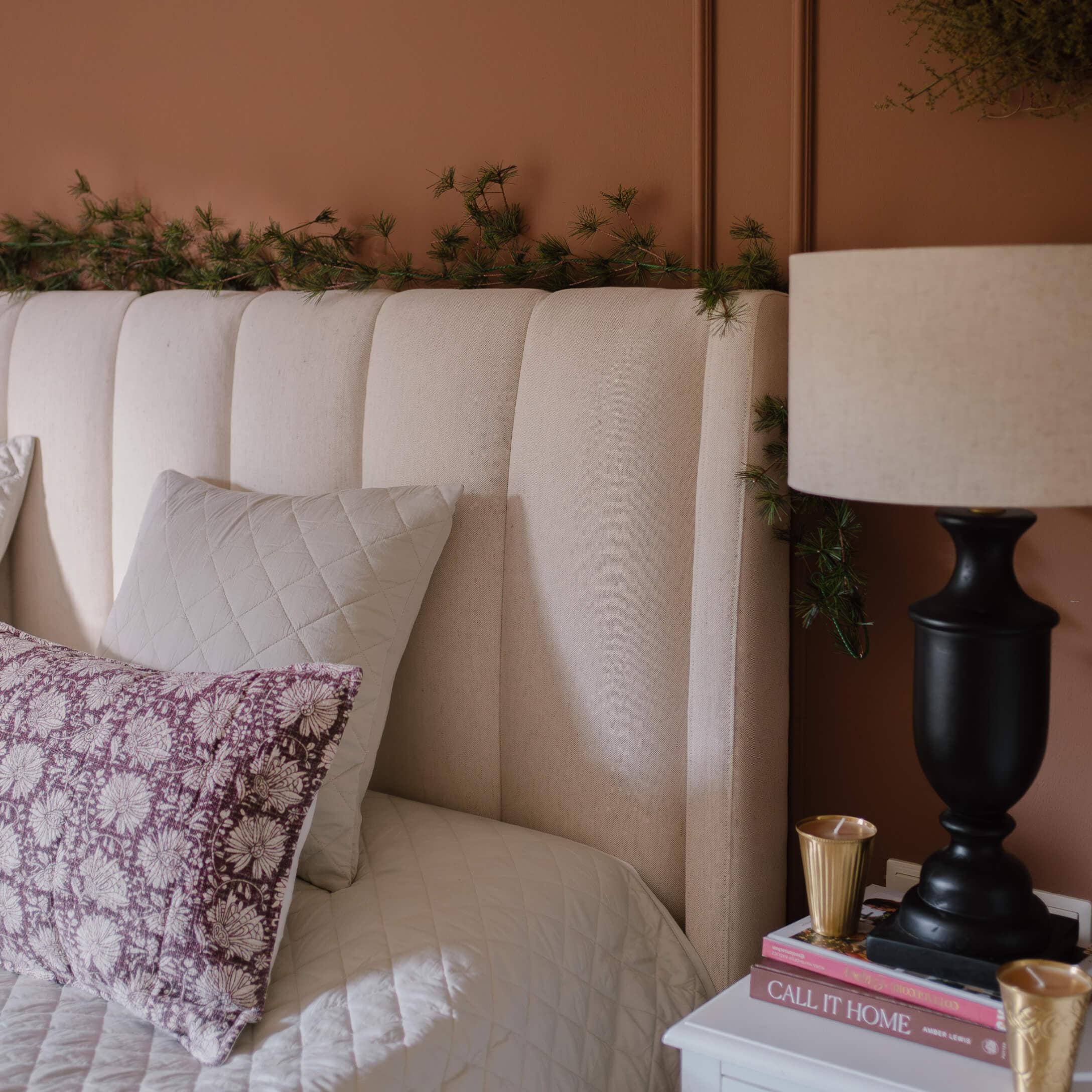 Tête de lit rembourrée beige avec coussins et lampe sur table de chevet dans une chambre chaleureuse