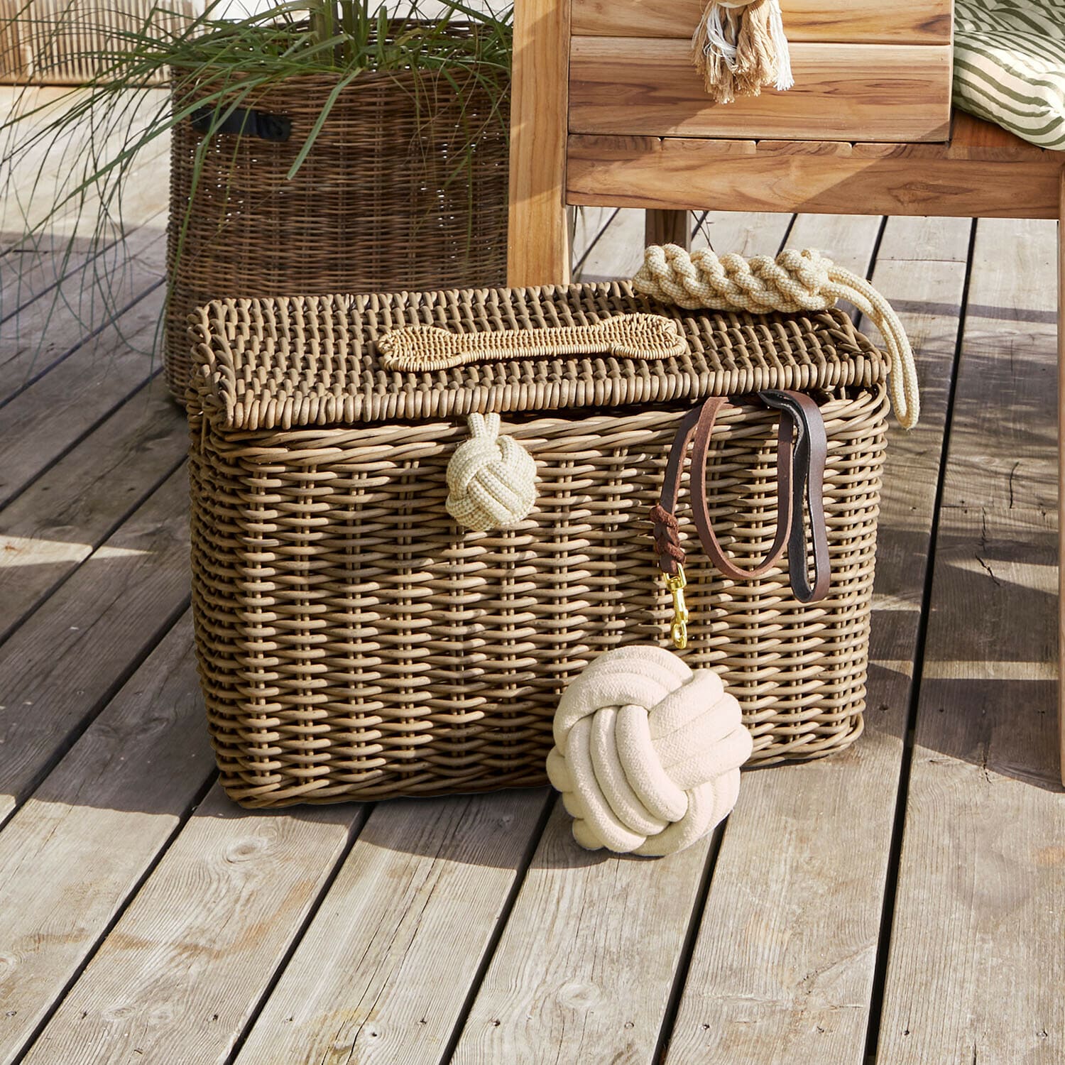 Panier en osier marron avec couvercle sur plancher en bois avec jouets pour chien beige