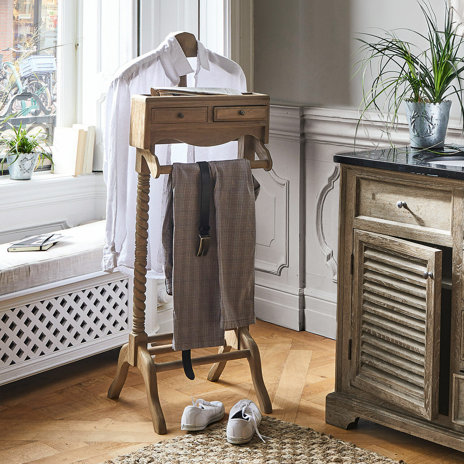 Valet de nuit Doncaster Valet en bois avec tiroirs et porte-pantalon dans une pièce claire avec parquet en bois