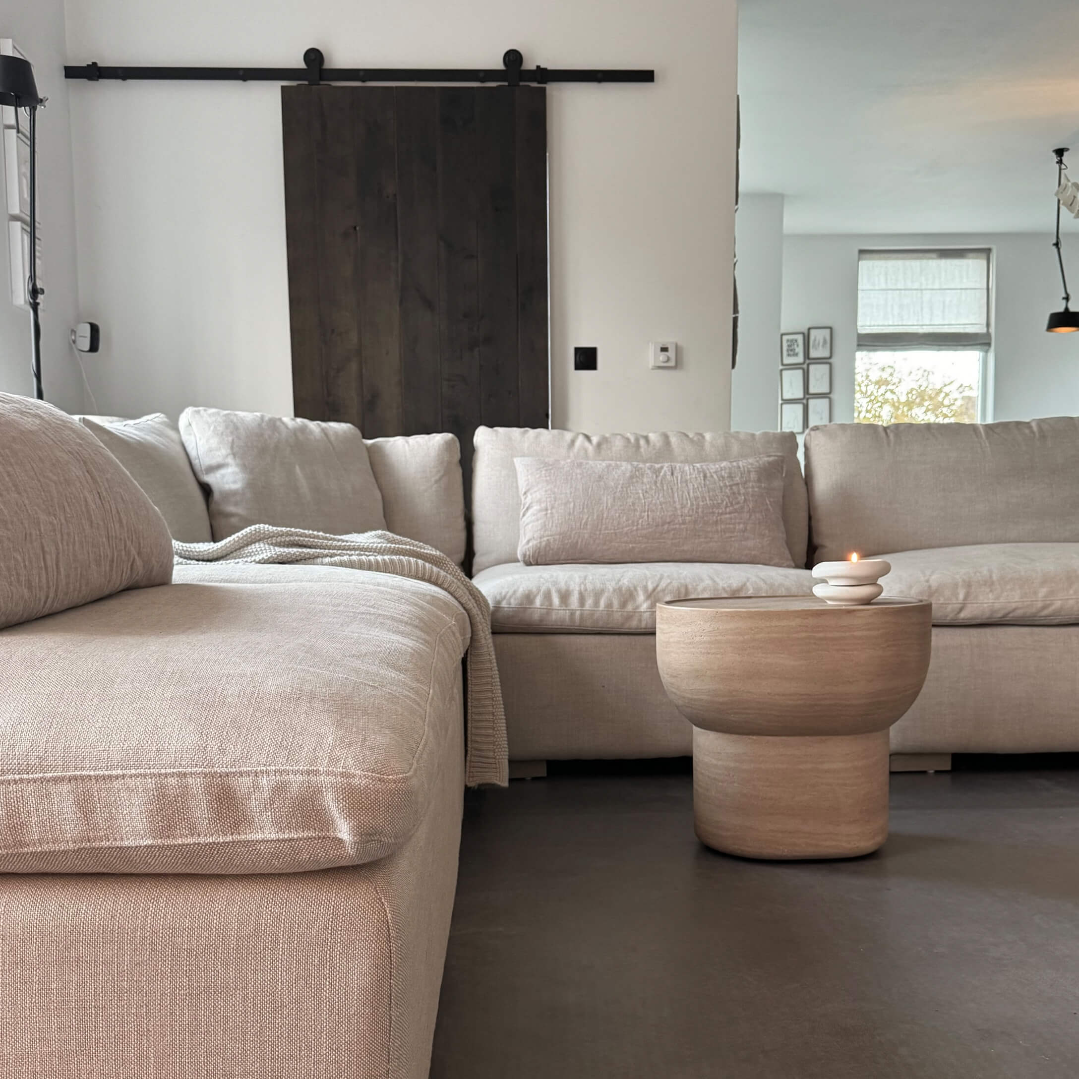 Beige stoffen hoekbank met houten salontafel en kaars in moderne woonkamer