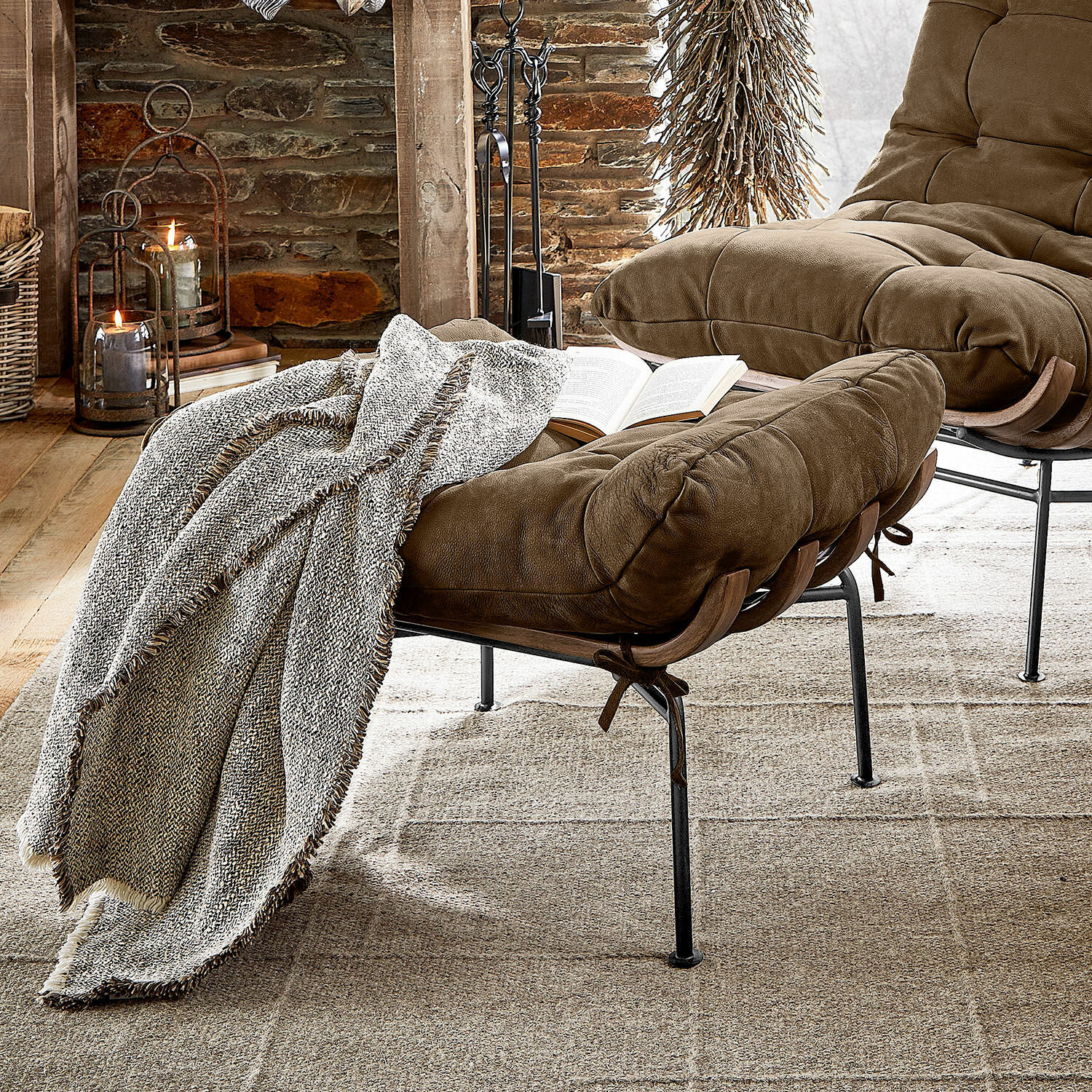 Footstool Horraine Bruine zachte stoffen fauteuil met voetenbank en grijze deken op beige tapijt in rustieke kamer