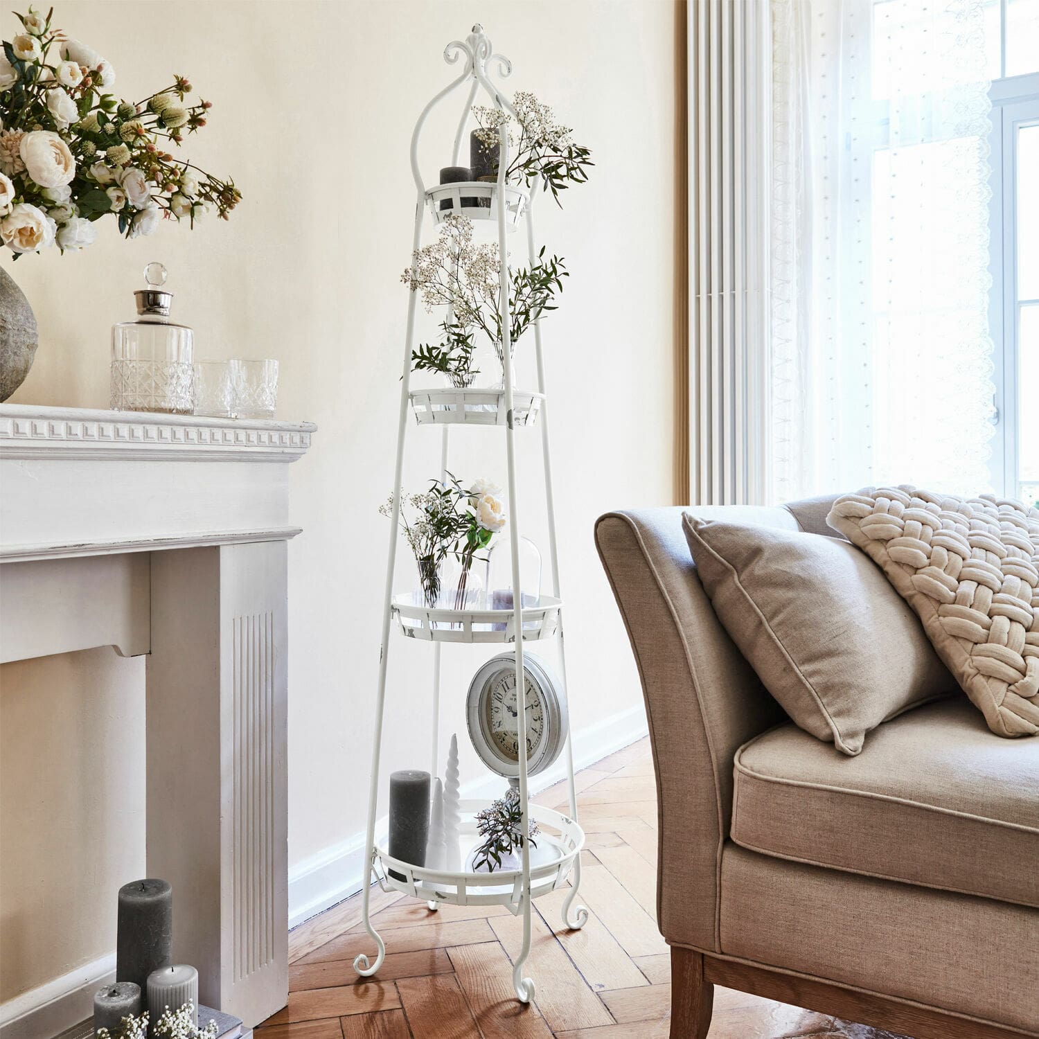 Présentoir à étages Ipas Étagère en métal blanc avec étagères et décorations florales dans un salon lumineux avec canapé beige
