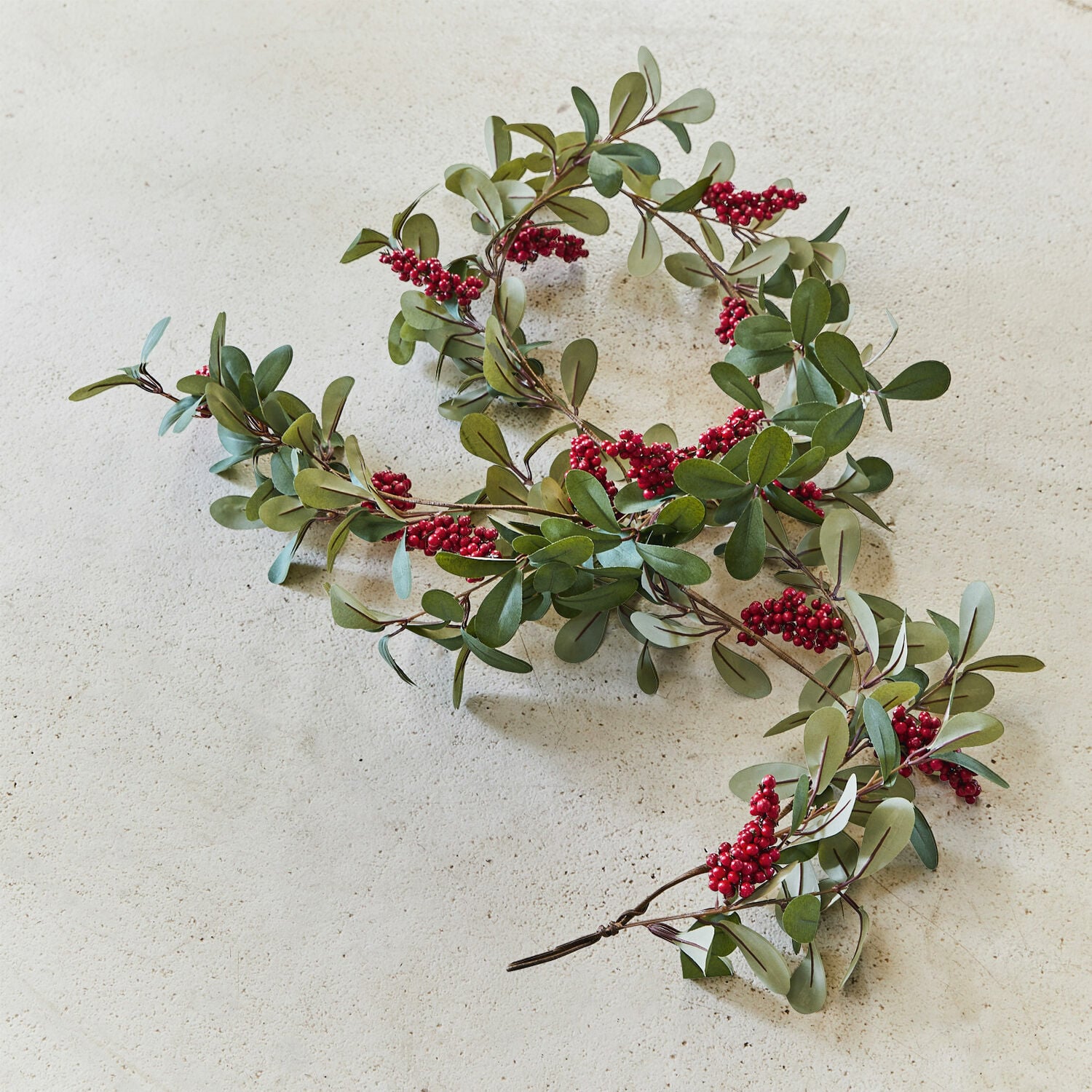 Guirlande Lenius Decoratieve slinger met groene bladeren en rode bessen op lichte achtergrond, feestelijke decoratie