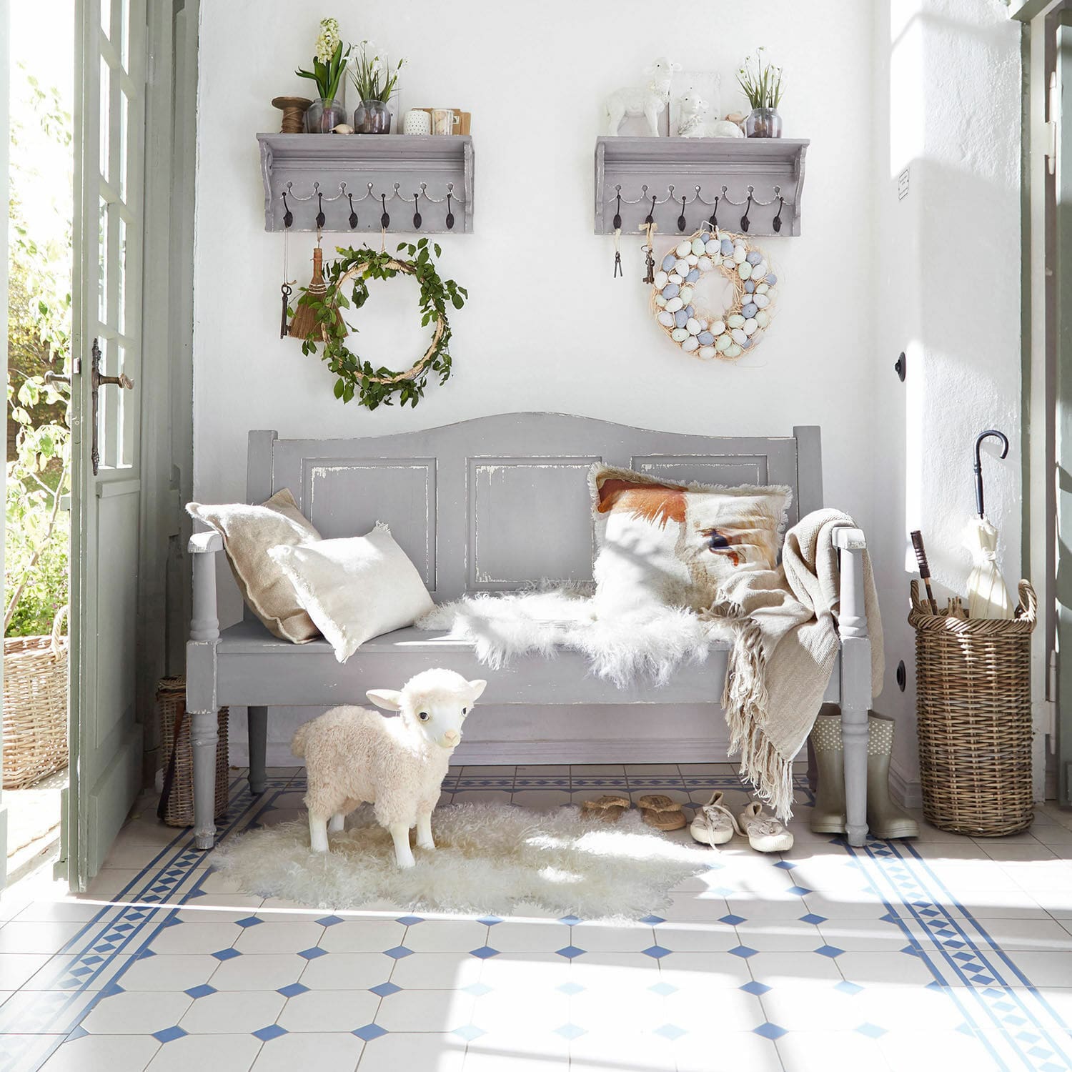 Banc en bois gris avec coussins et figurine de mouton décorative sur sol carrelé clair