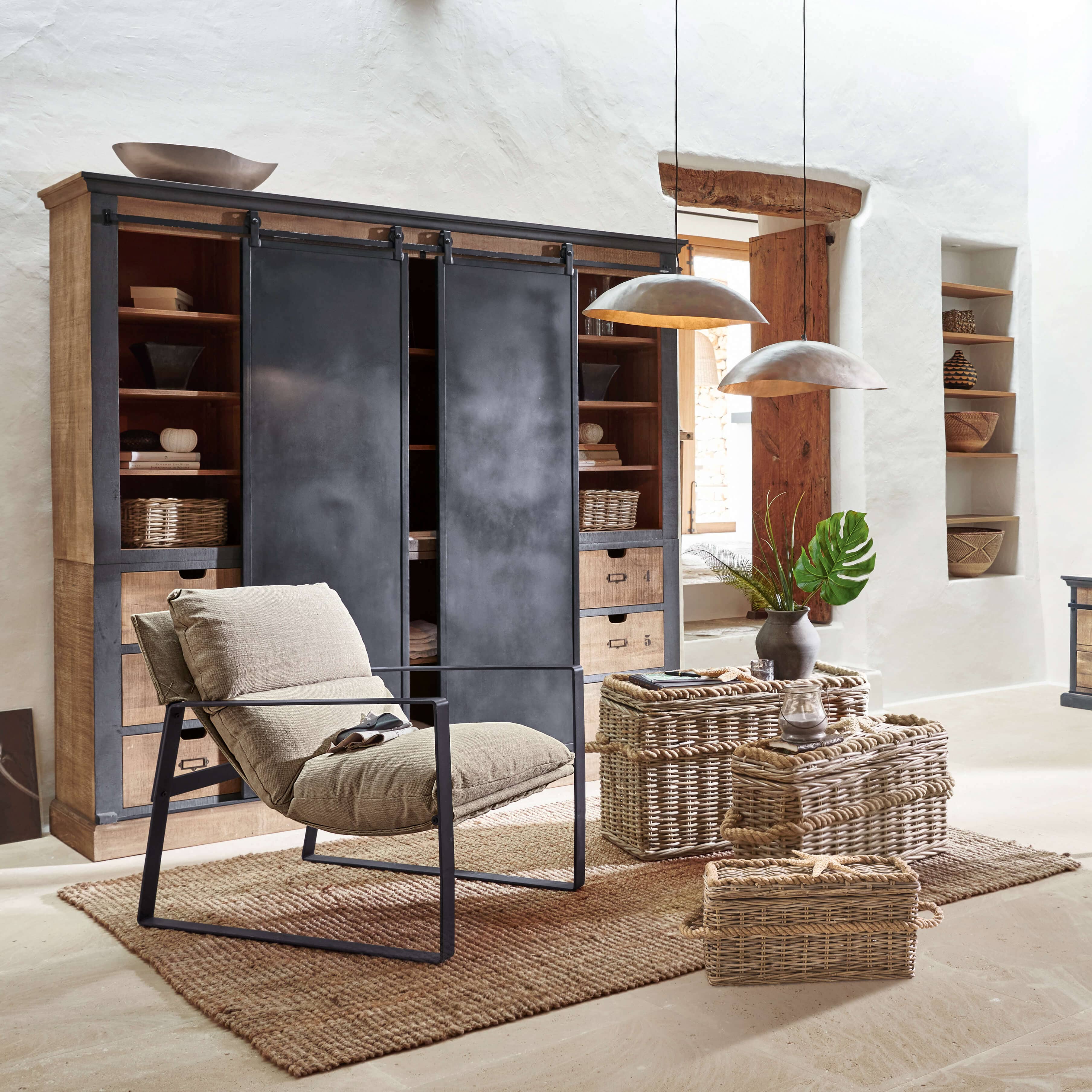 Comfortabele stoel met beige stof en metalen frame in rustieke woonkamer met rieten manden