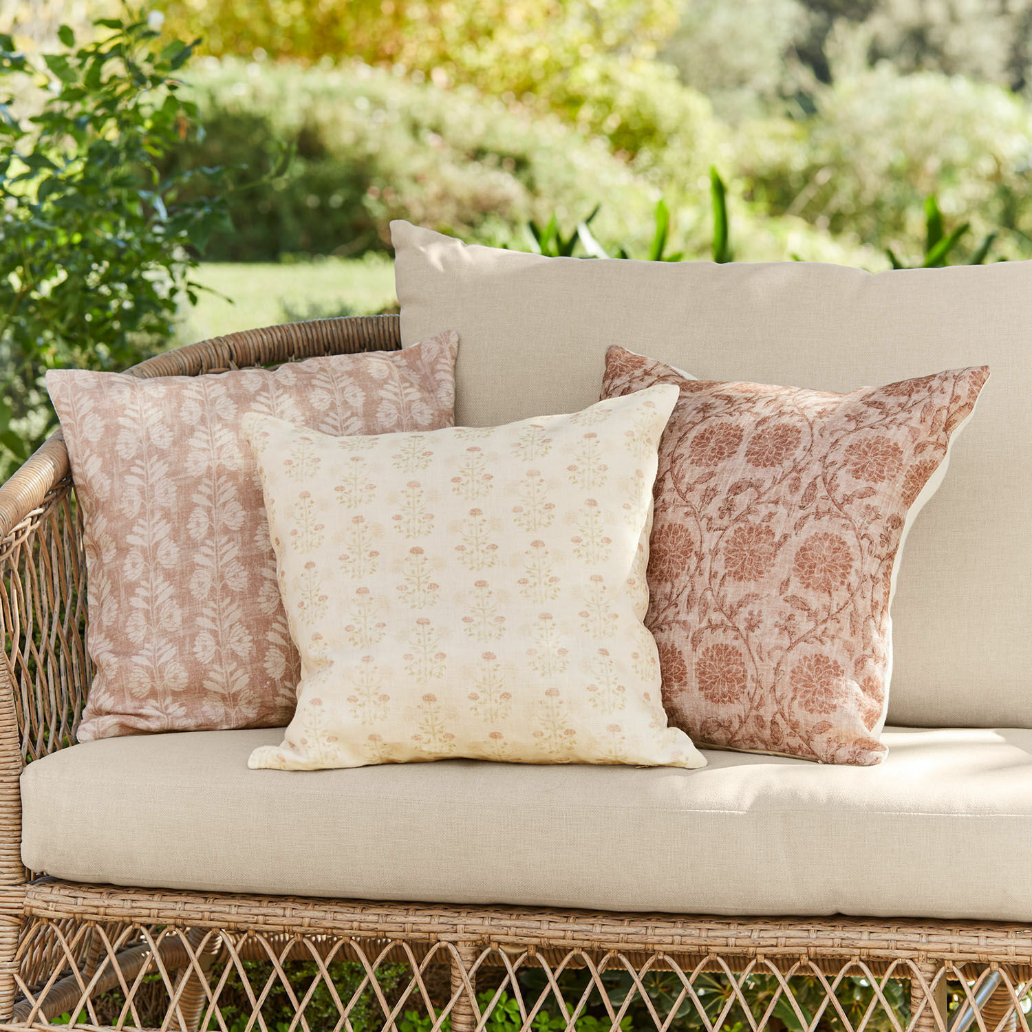 Kussenhoes set van 3 Tarouja Set van drie decoratieve katoenen kussens in beige-roze patronen op een rotan tuinbank