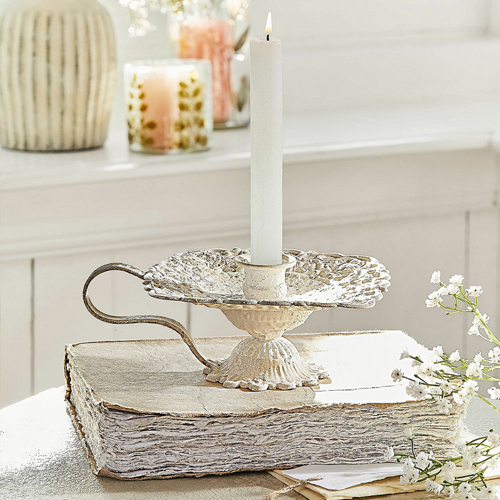 Vintage metalen kandelaar in crèmekleur op wit boek, tafeldecoratie met witte bloemen