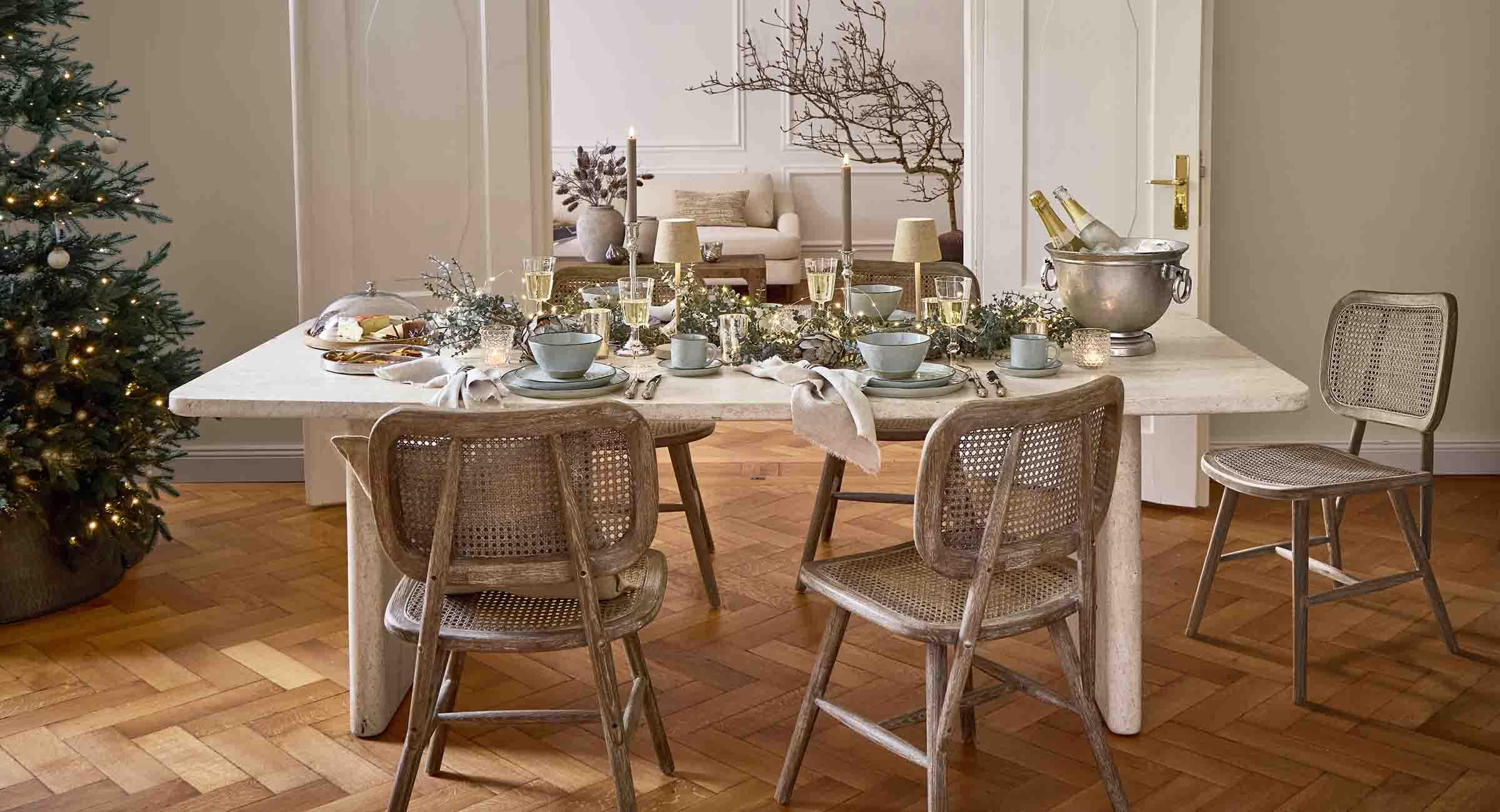 Table à manger élégante en marbre clair avec chaises en bois et rotin, décorations de fête lumineuses