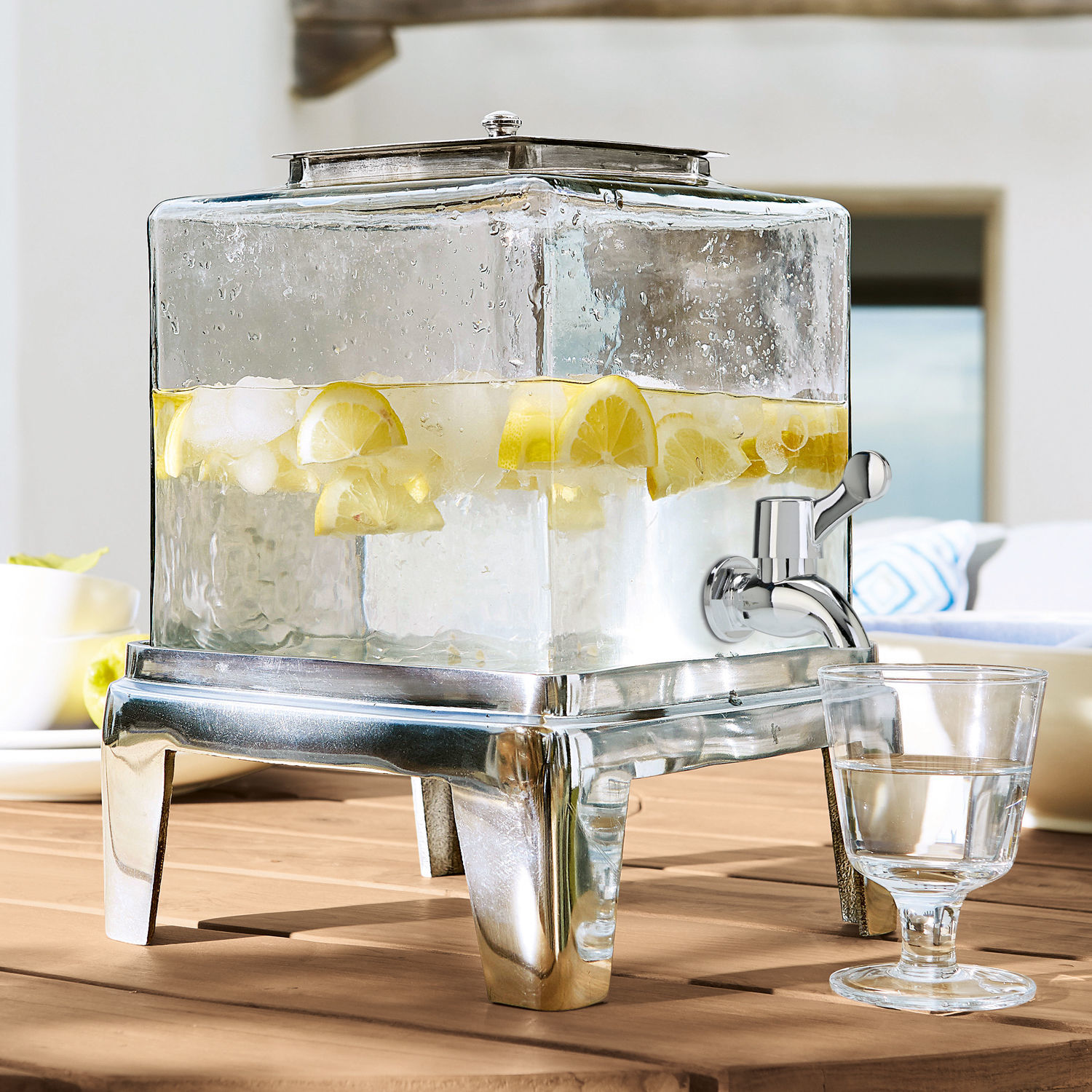 Drankdispenser Osric Glazen drankendispenser met metalen voet en kraan, gevuld met water en citroen