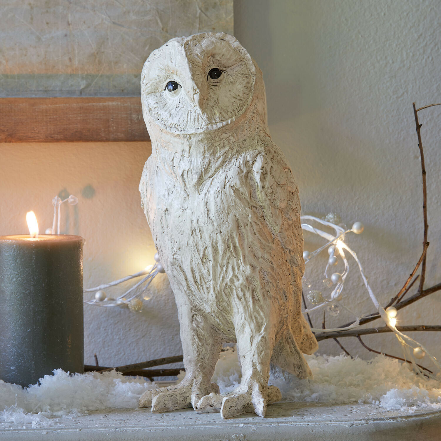 Chouette décorative Heriette Figurine de chouette décorative en matériau clair sur une table festive avec bougie et guirlande lumineuse