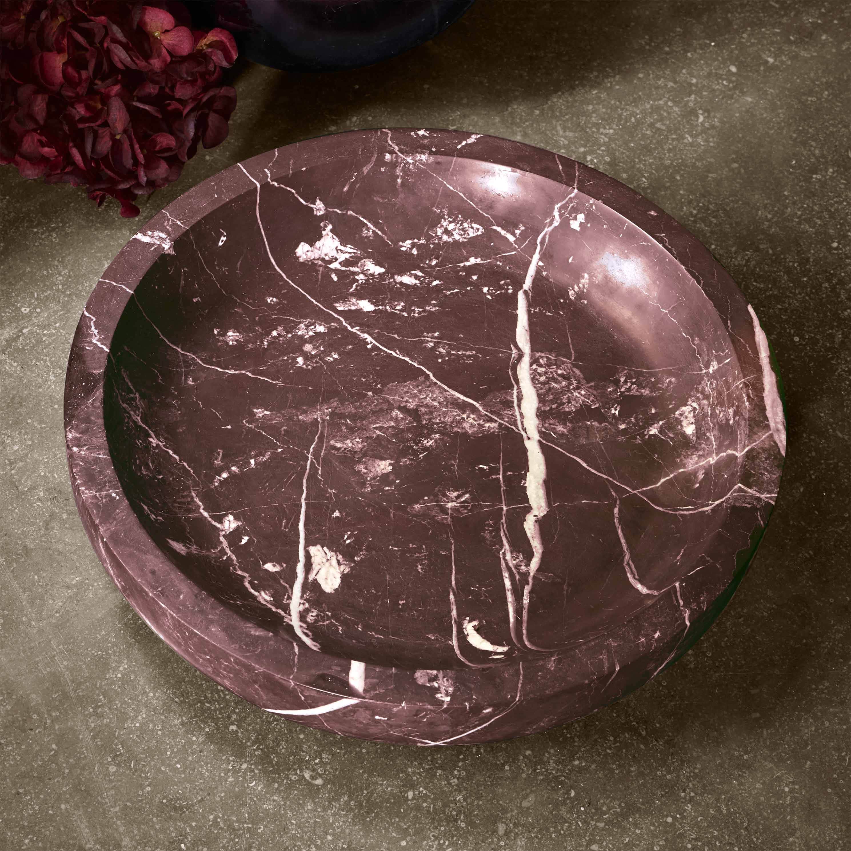 Bol en marbre rouge rond avec veines blanches sur fond gris, décoration élégante