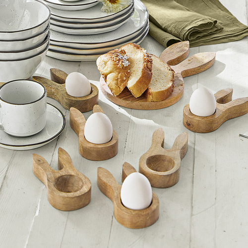 Houten eierhouders in konijnenorenvorm op witte tafel met brood en servies