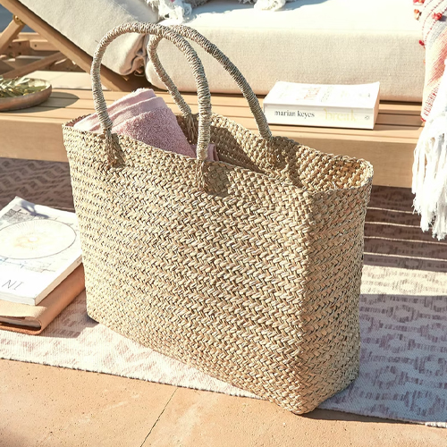 Grote gevlochten tas van zeegras in natuurlijke kleur, ideaal voor strand of boodschappen.