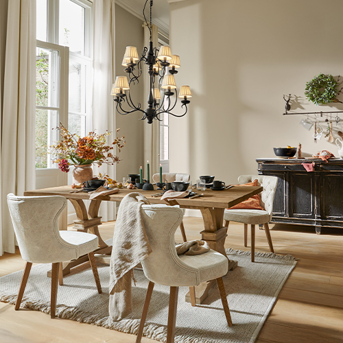 Salle à manger avec table en bois, chaises rembourrées crème, décor floral et lustre noir élégant