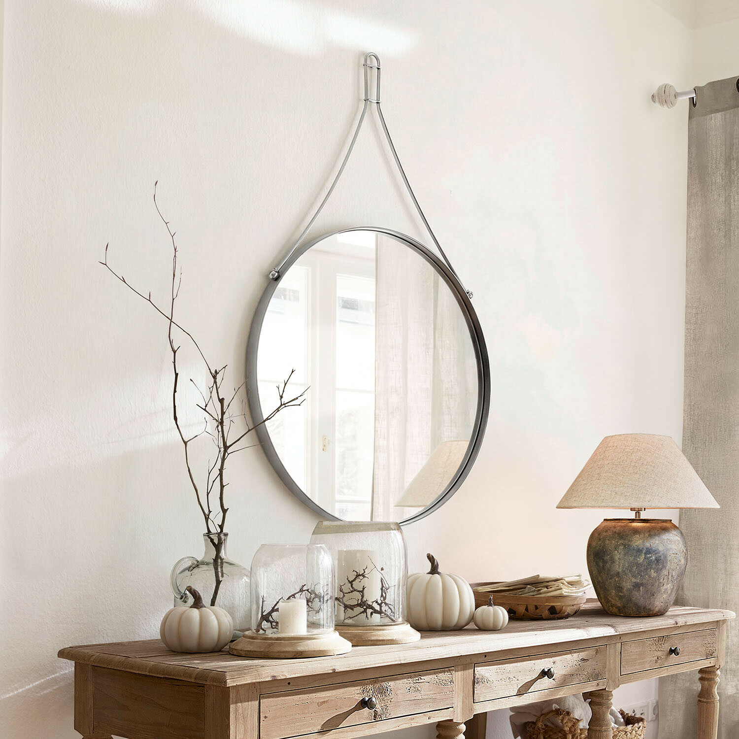 Miroir Célivaux Miroir rond suspendu avec sangle métallique argentée au-dessus d'une console en bois décorée
