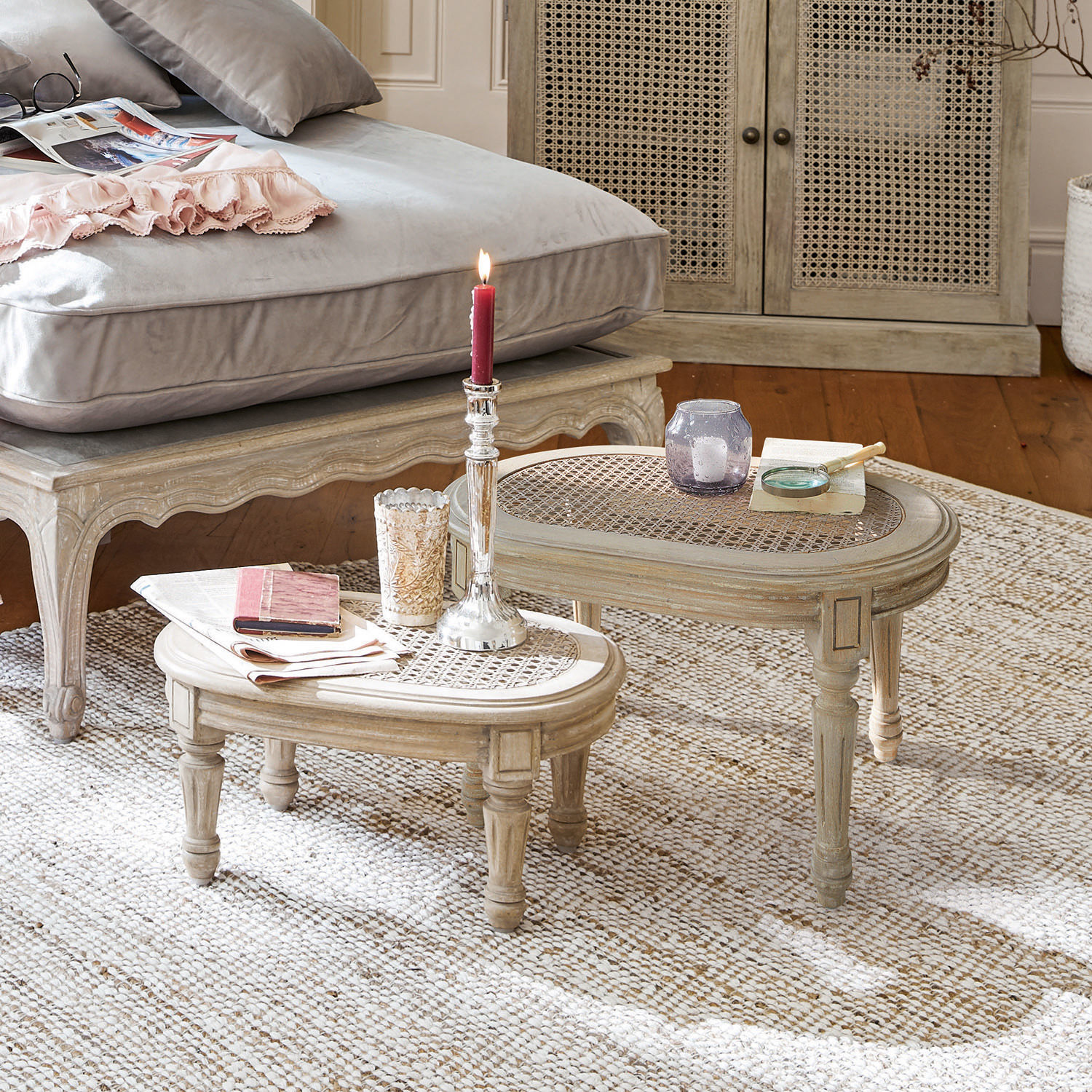 Deux tables basses beige en bois et rotin sur un tapis clair dans un salon chaleureux