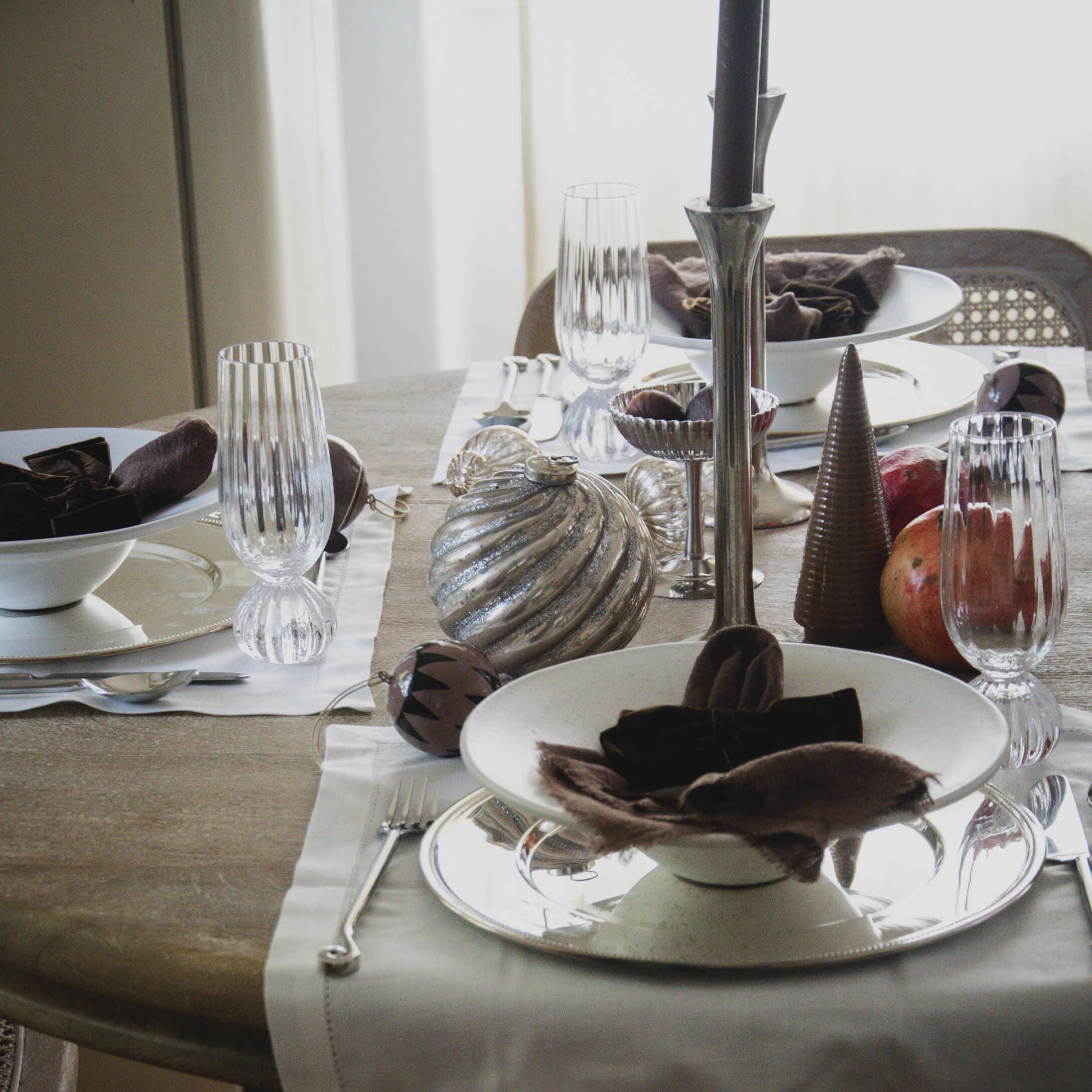 Table élégamment dressée avec vaisselle blanche, verres en verre et décorations naturelles pour repas raffiné