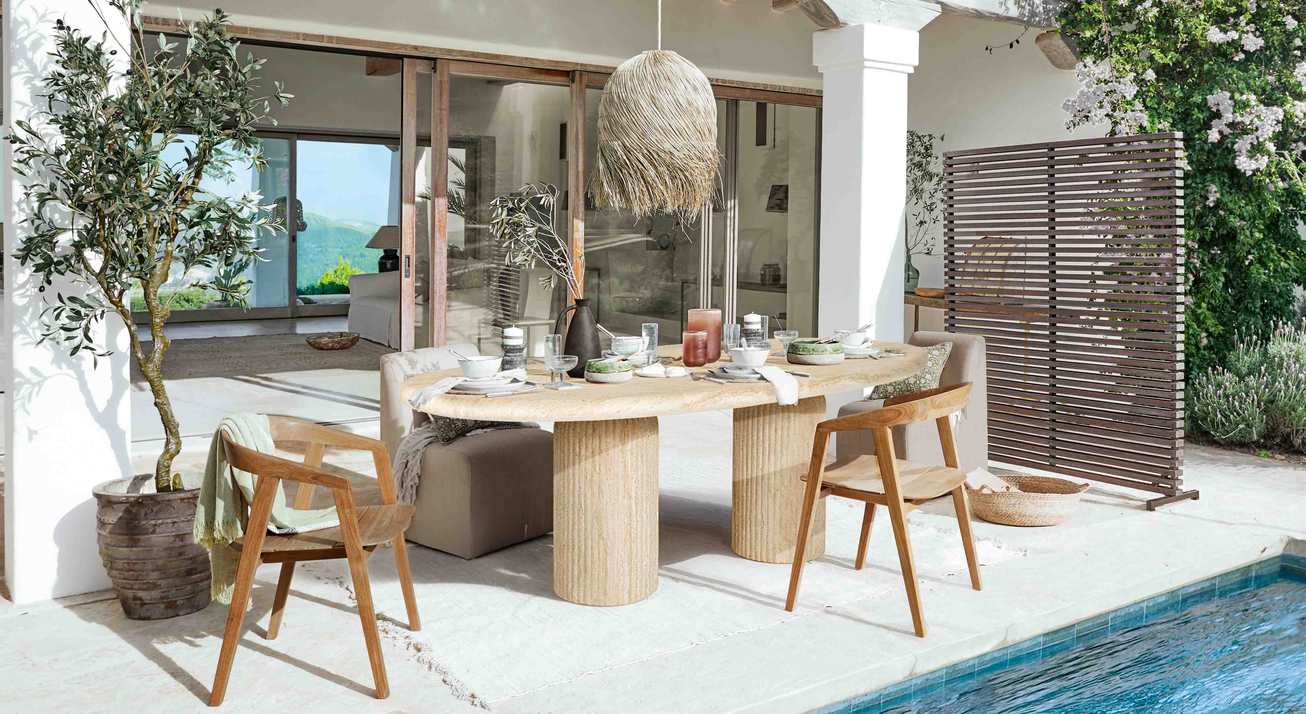 Buiten eetgedeelte met stenen tafel en houten stoelen bij het zwembad in natuurlijke stijl