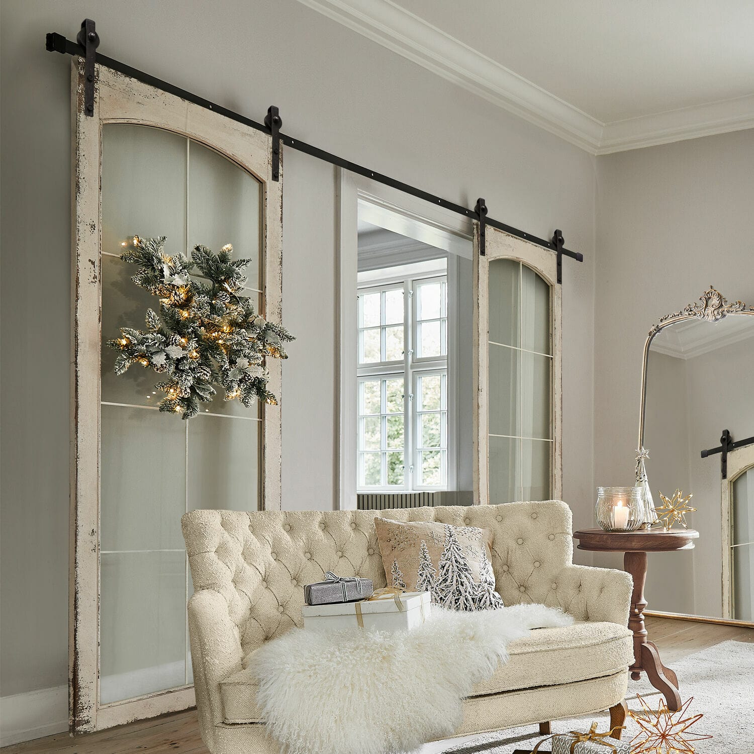 Double porte coulissante Incles Canapé beige capitonné avec plaid en fausse fourrure et décorations de Noël dans un salon lumineux avec portes coulissantes