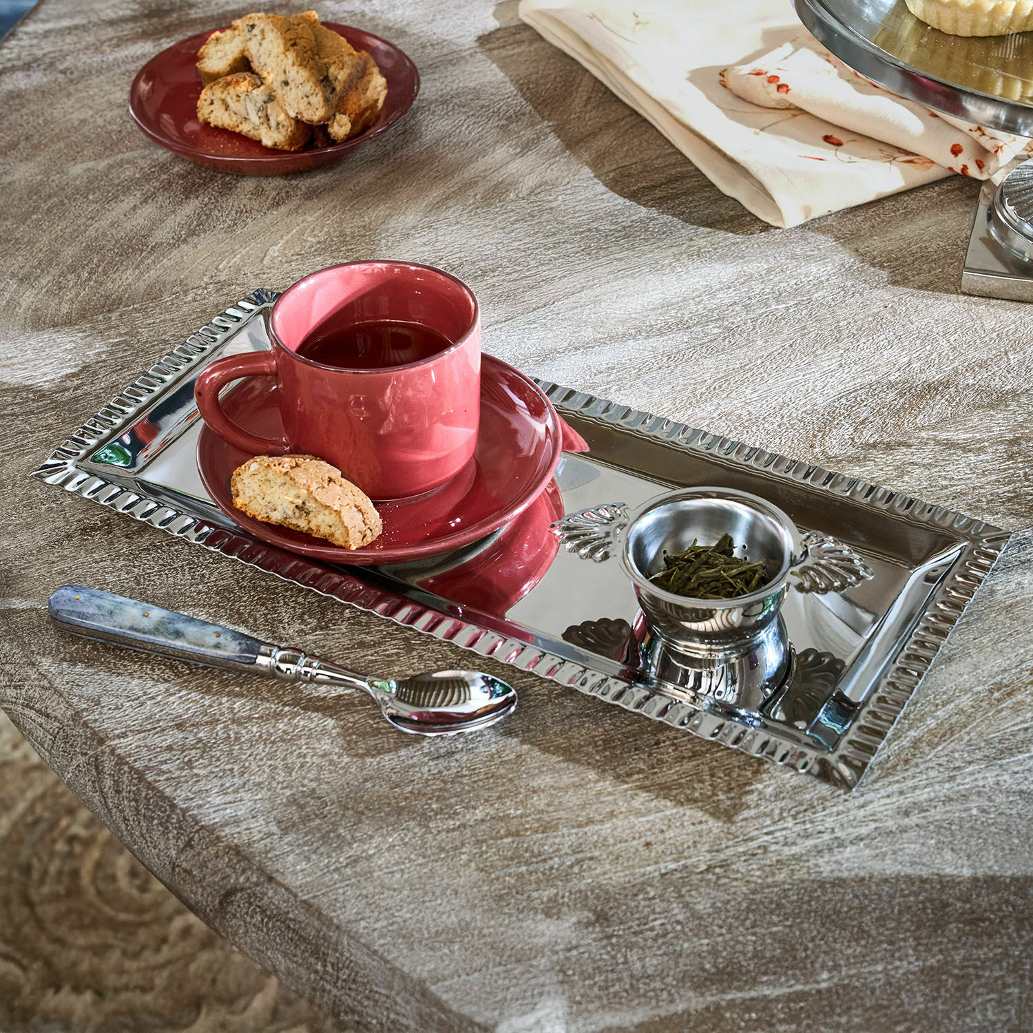 Theeset Arivelle Rechthoekig zilverkleurig metalen dienblad met rode kop, thee en koekje op houten tafel