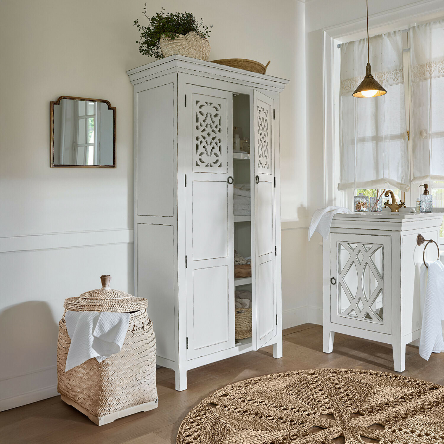 Armoire blanche en bois avec portes ajourées et panier en rotin tressé dans une salle de bain lumineuse