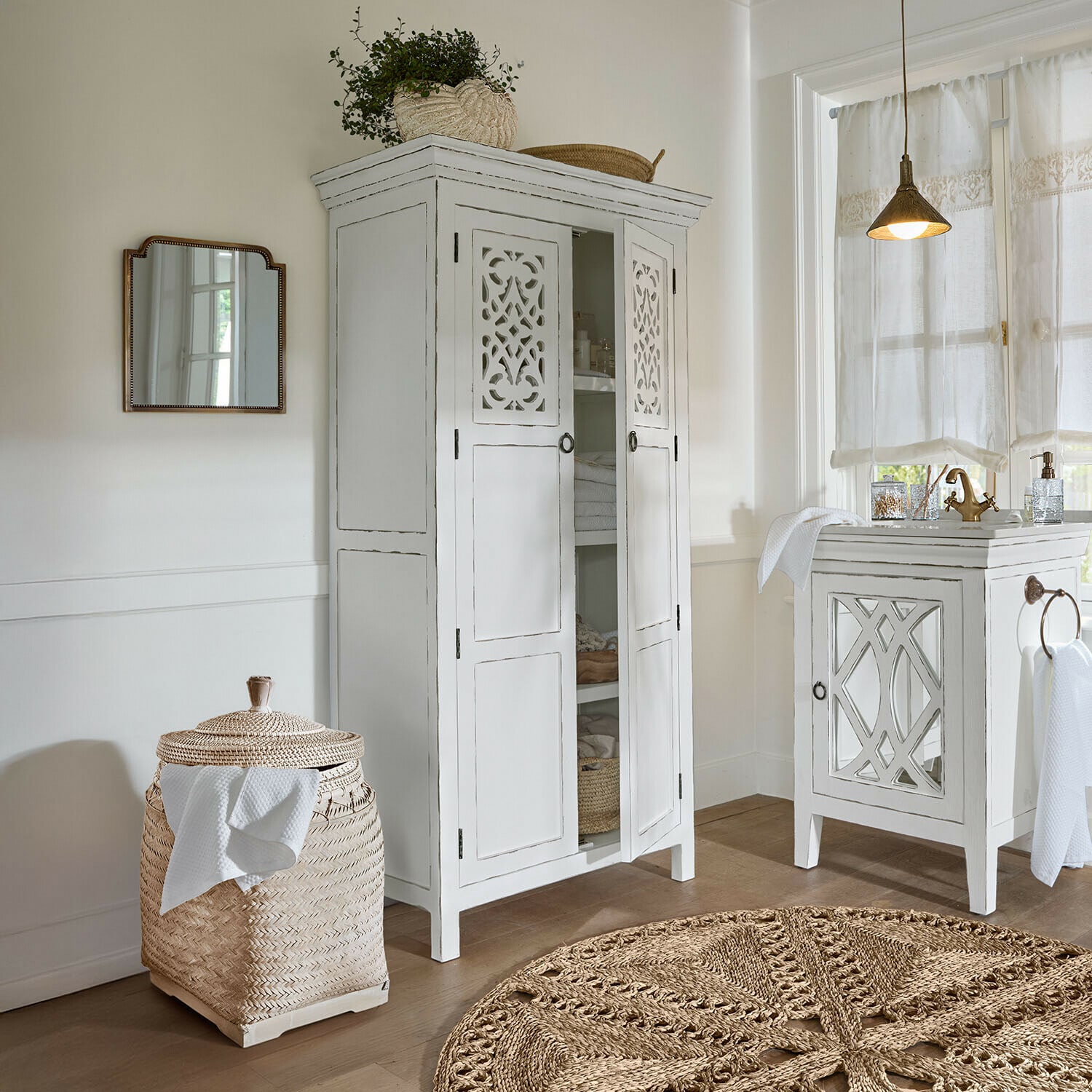 Kast Marvoux Witte houten kast met geperforeerde deuren en gevlochten rotanmand in lichte badkamer