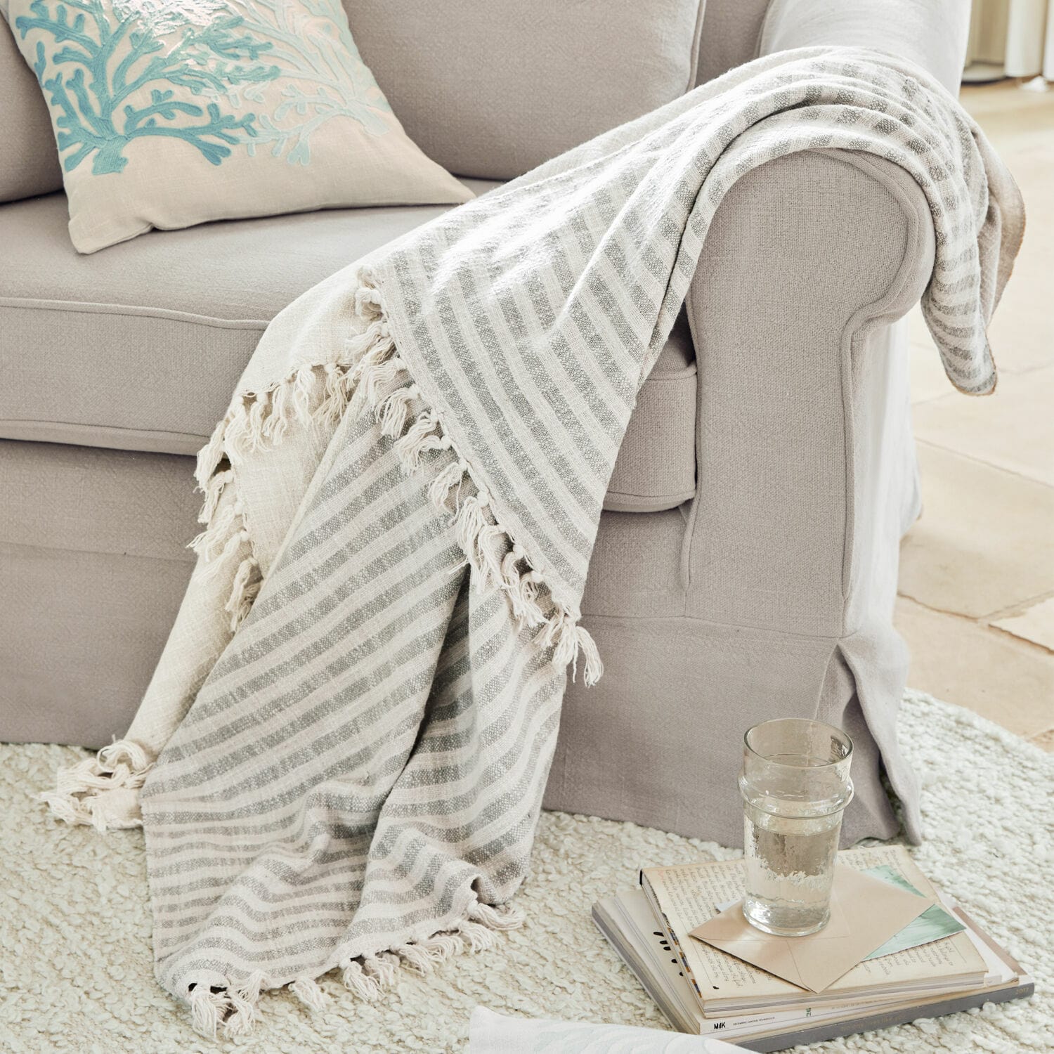 Plaid Marpent Plaid beige à rayures avec franges sur un canapé gris clair, accessoire cosy pour salon