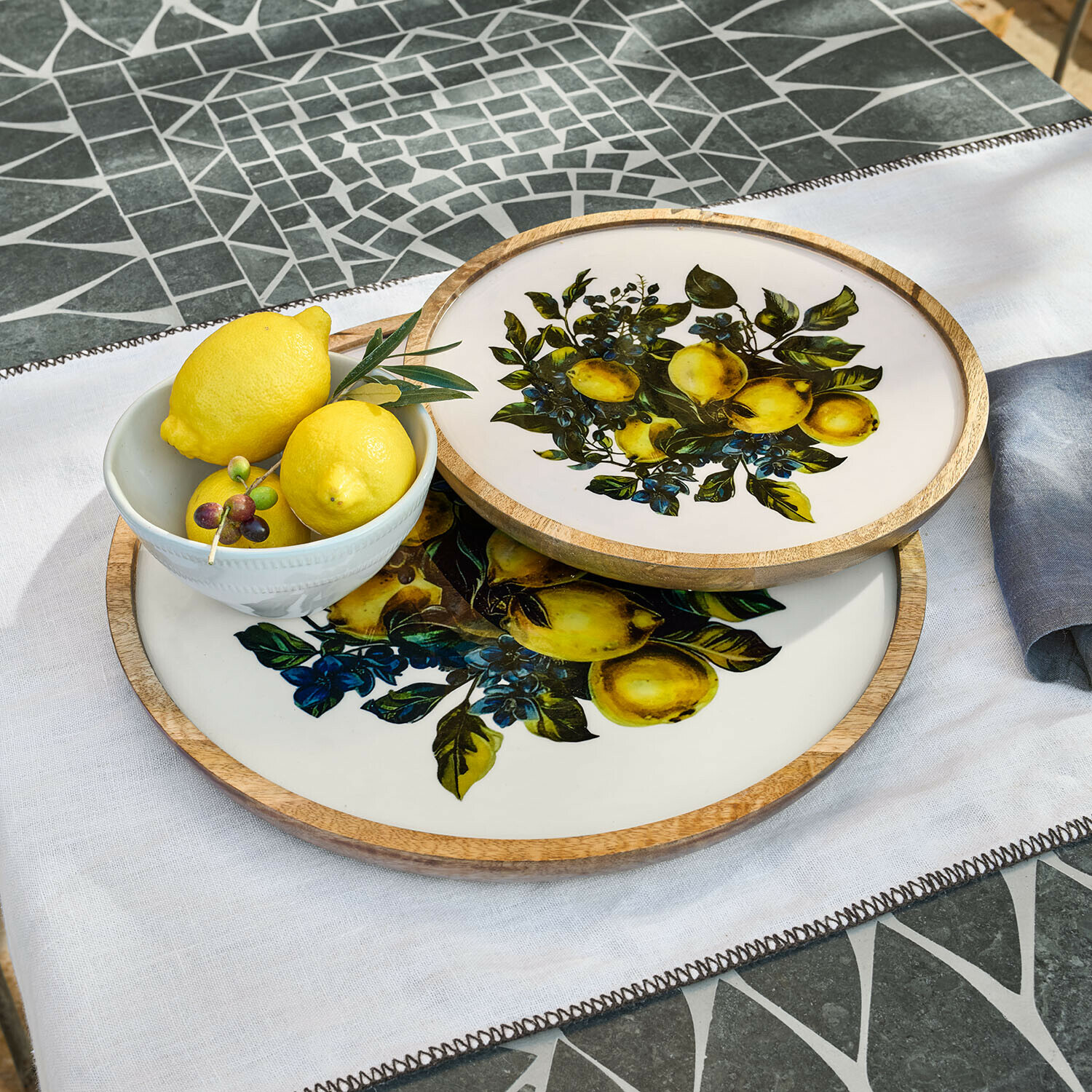 Dienblad set van 2 Solianne Twee ronde dienbladen van hout en keramiek met citroendesign op witte achtergrond op mozaïektafel