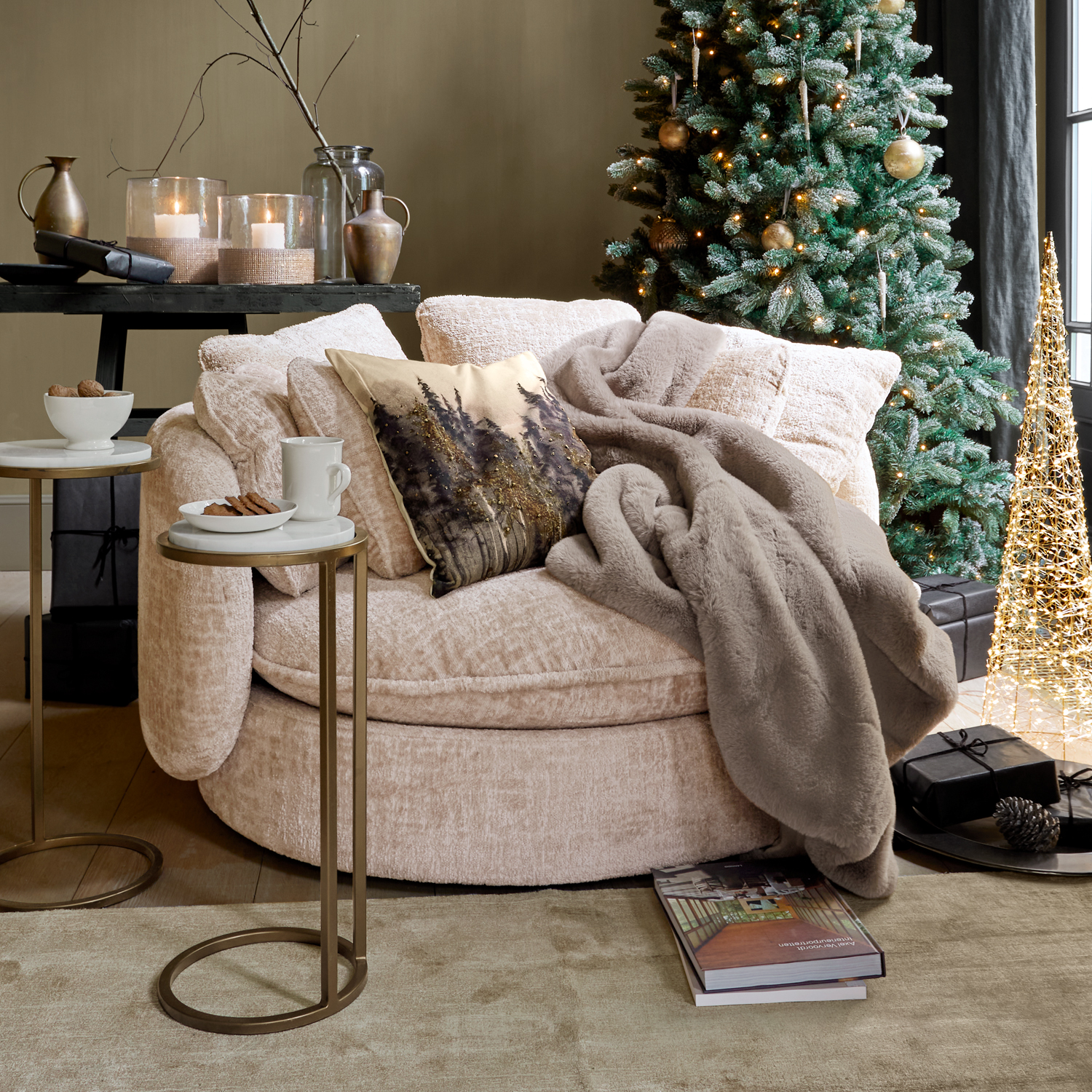 Beige ronde fauteuil met zachte deken en decoratief kussen naast kerstboom en bijzettafels