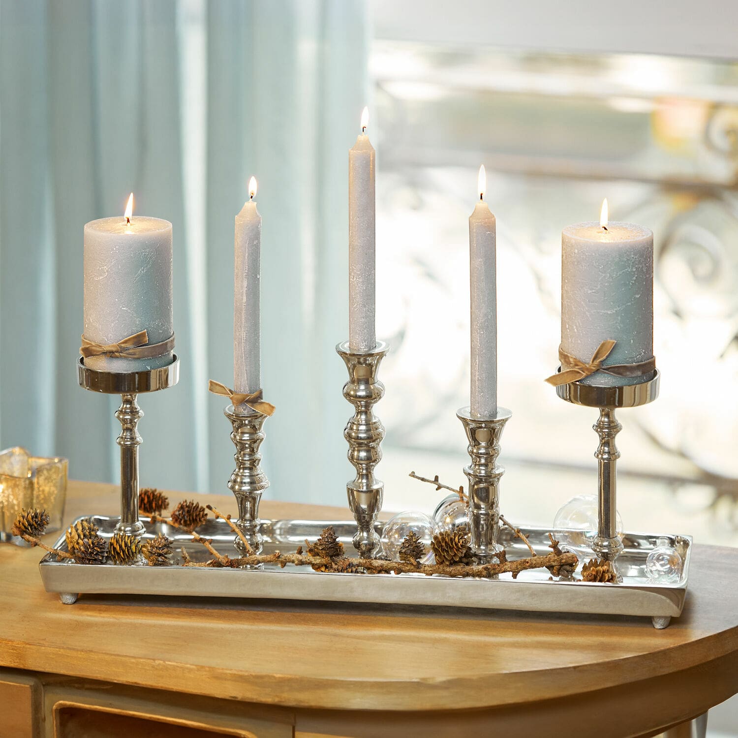 Kaarsenplateau Alirra Metalen kandelaar met vijf grijze kaarsen en dennenappeldecoratie op houten tafel